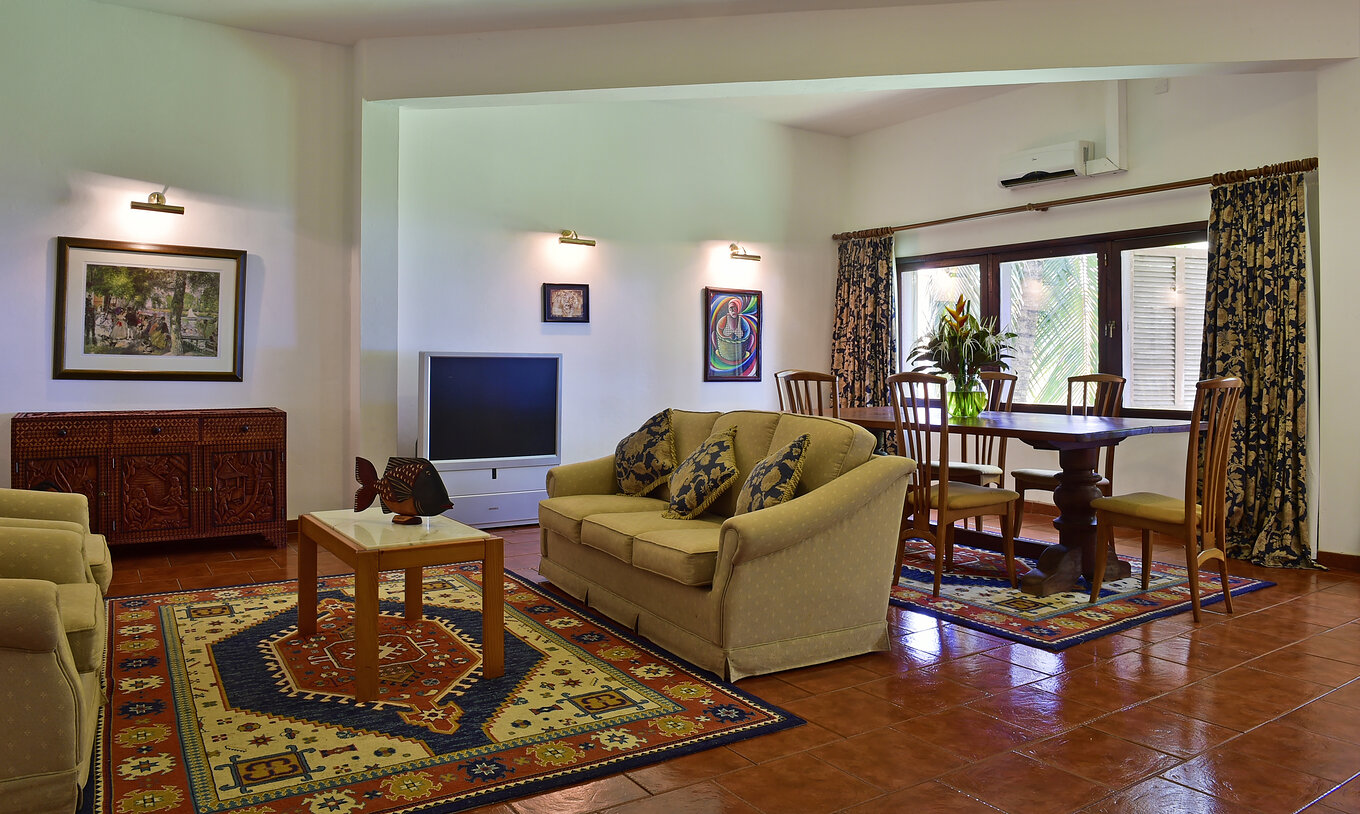 The Presidential Suite at Pestana Miramar São Tomé has a living room with three sofas, a dining table, and a television