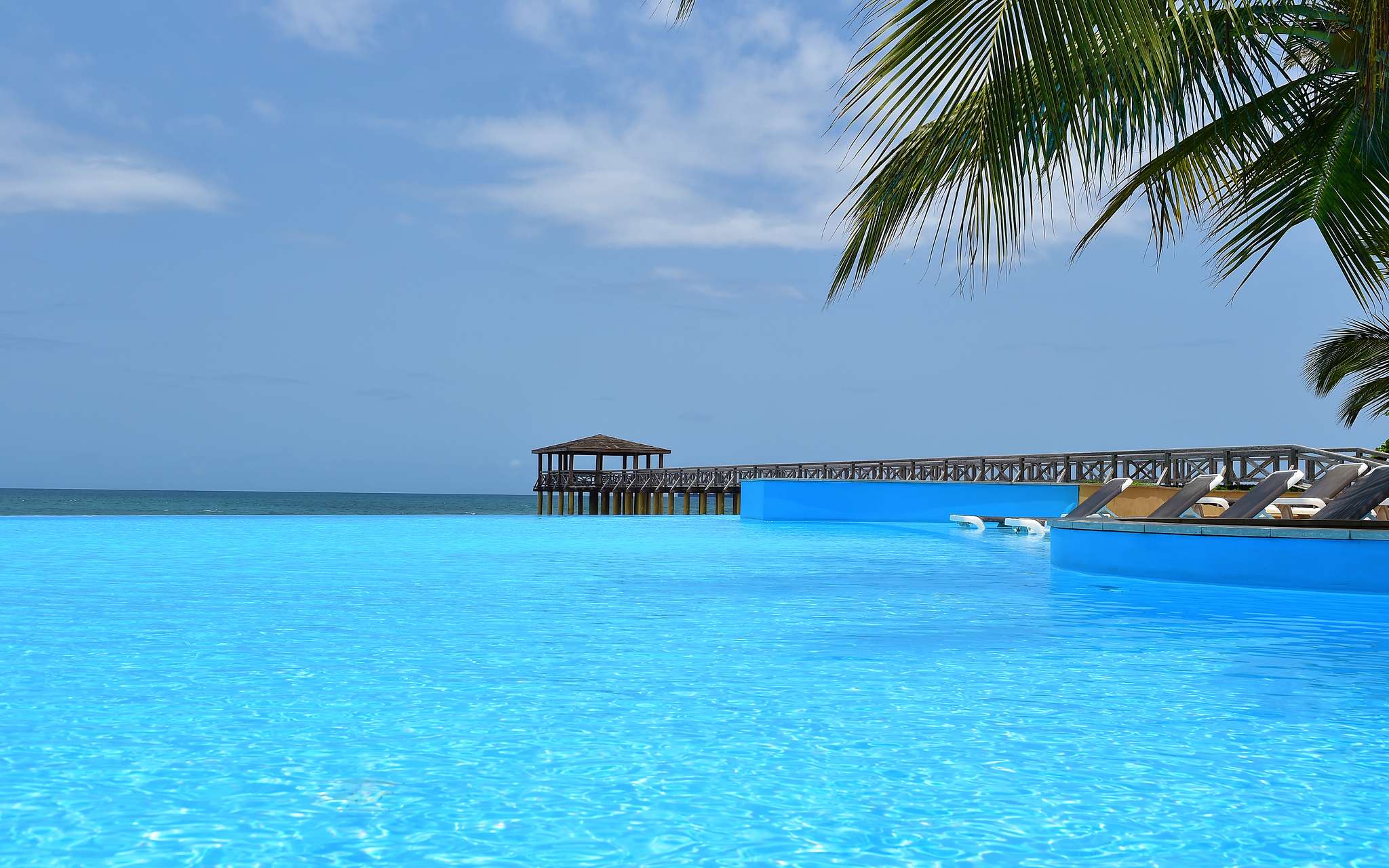 Paradise view of the pool at Pestana São Tomé merging with the crystal-clear sea, an idyllic tropical setting