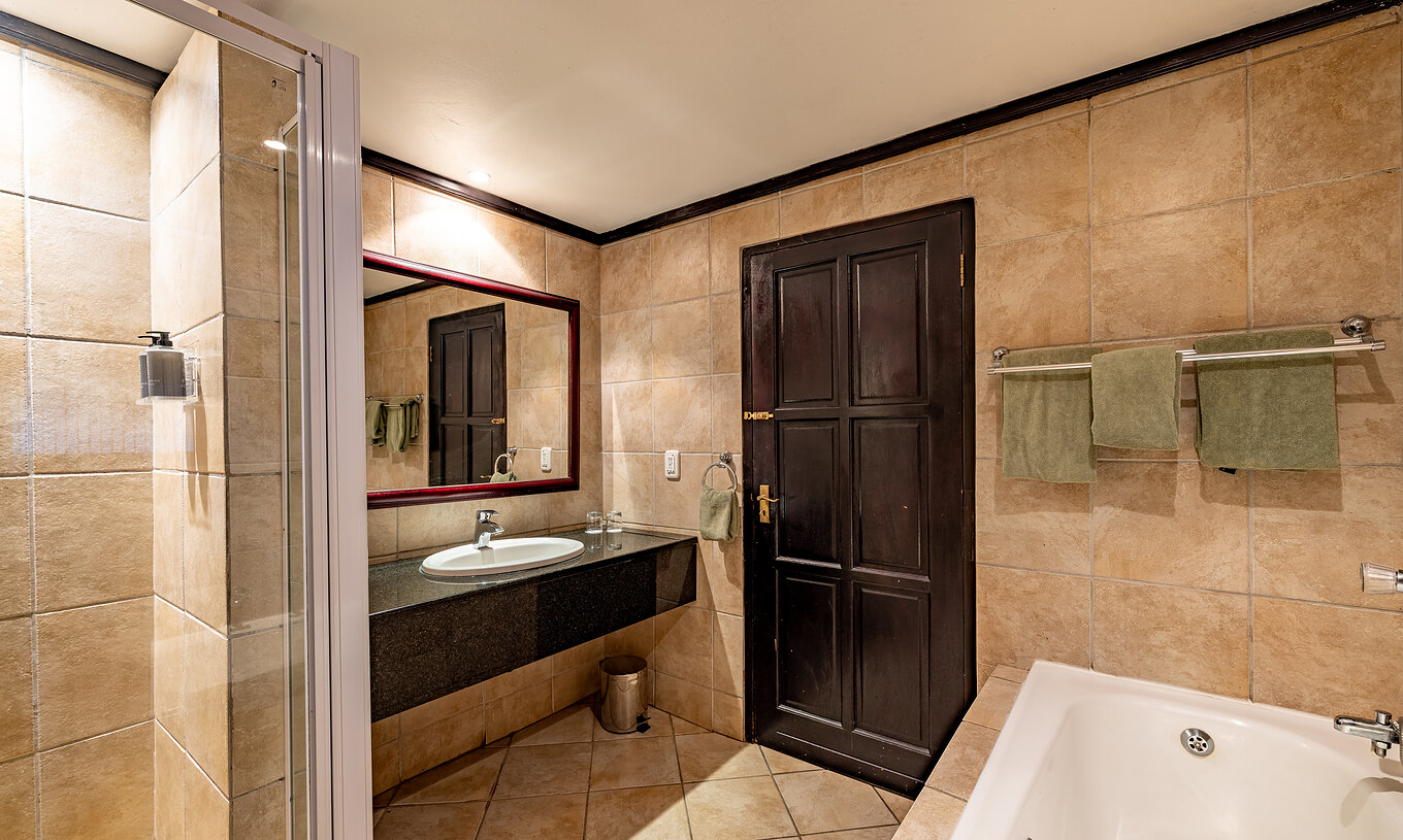 The Premium Room at Pestana Kruger Lodge has a bathroom with bathtub, shower and sink with mirror