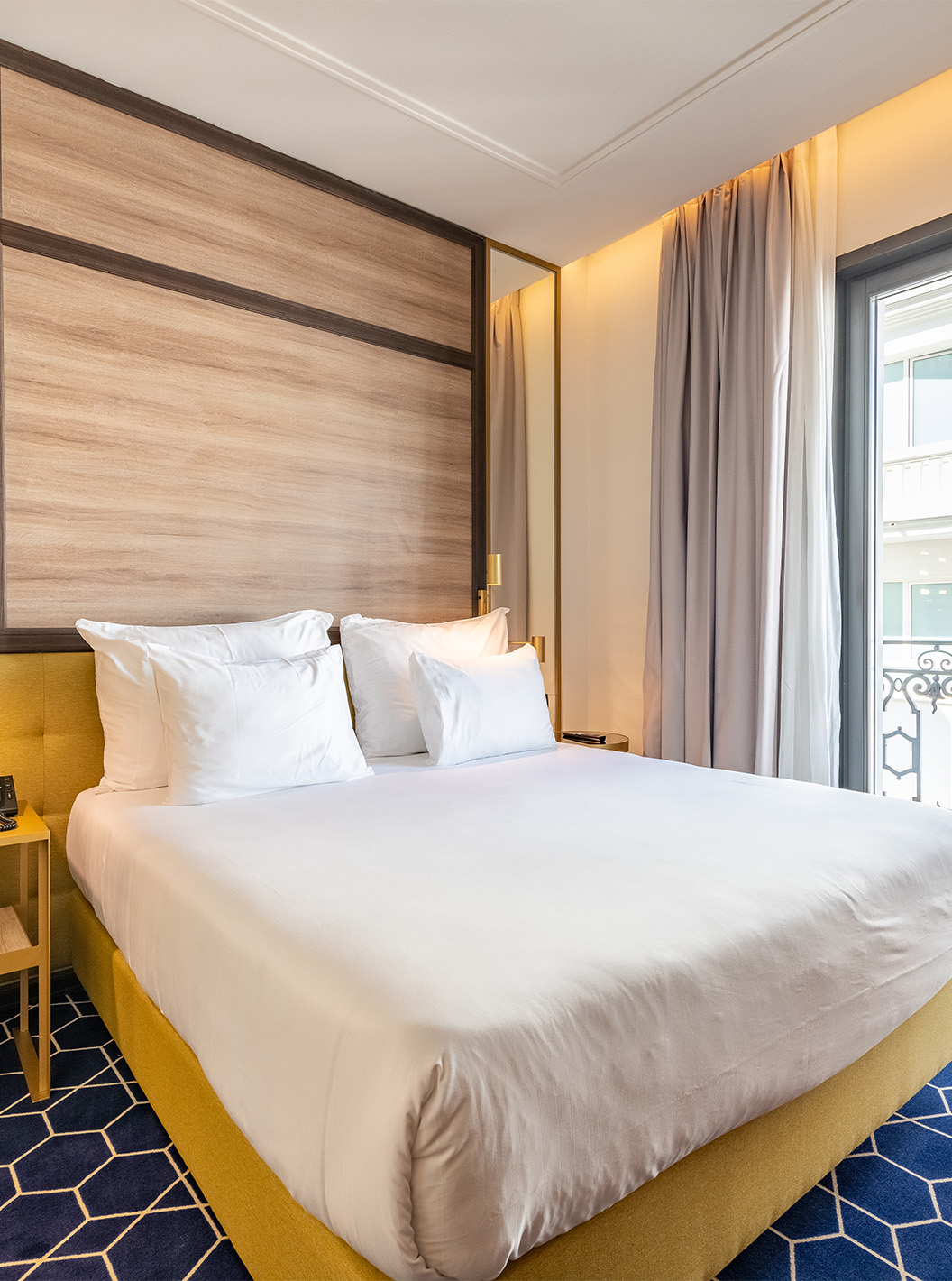 The Premium Room with Balcony at Pestana CR7 Gran Vía Madrid features a double bed and windows overlooking a white building