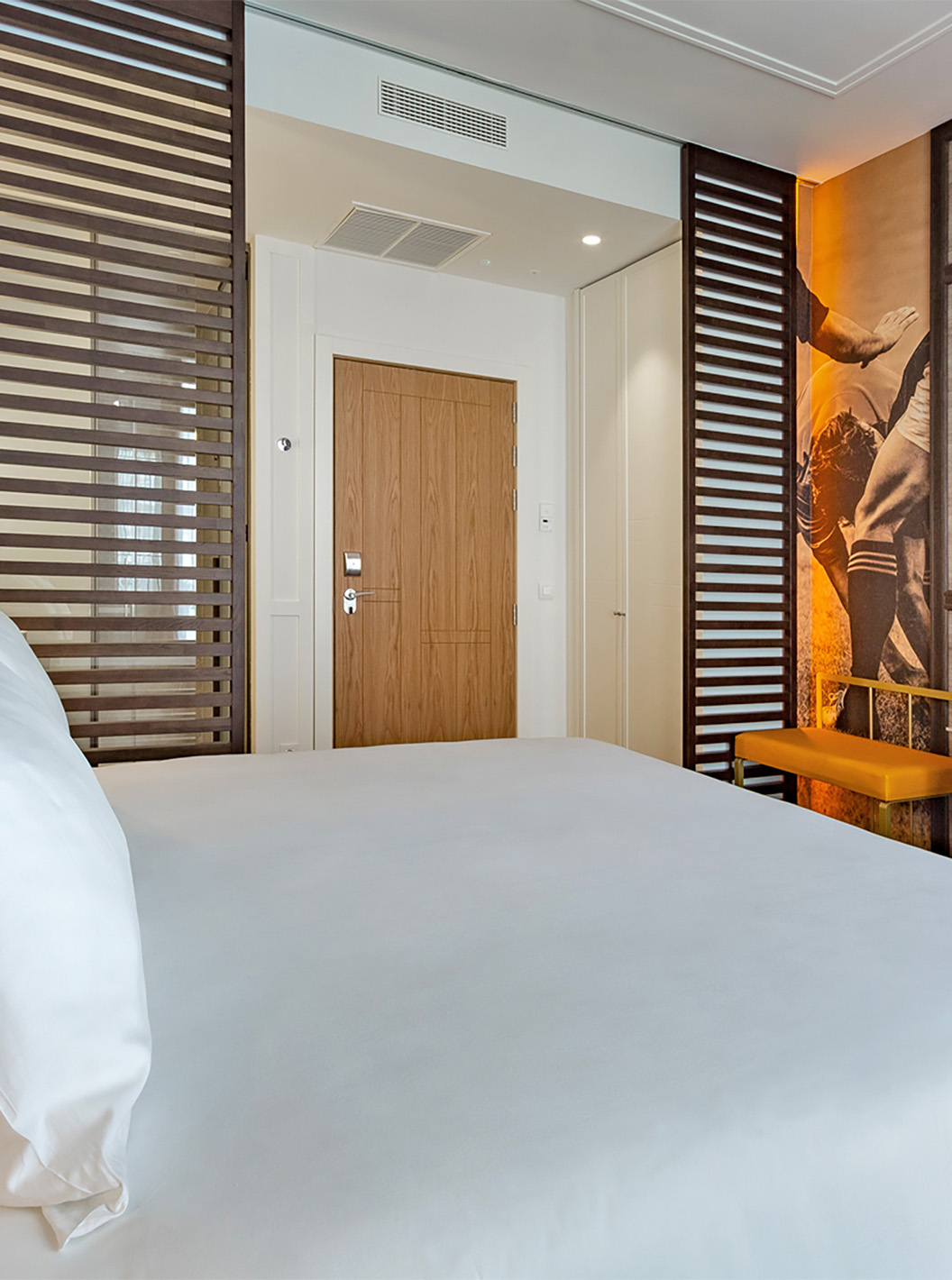 The Premium Room at Pestana CR7 Gran Vía Madrid features a double bed, desk with chair, lamp, bench, and television