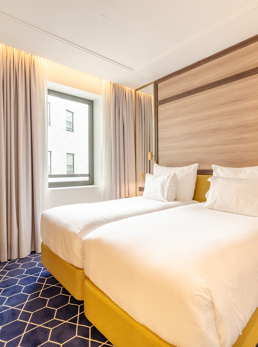 The Superior Room at Pestana CR7 Gran Vía Madrid features two beds, a chair, and a window facing the interior courtyard