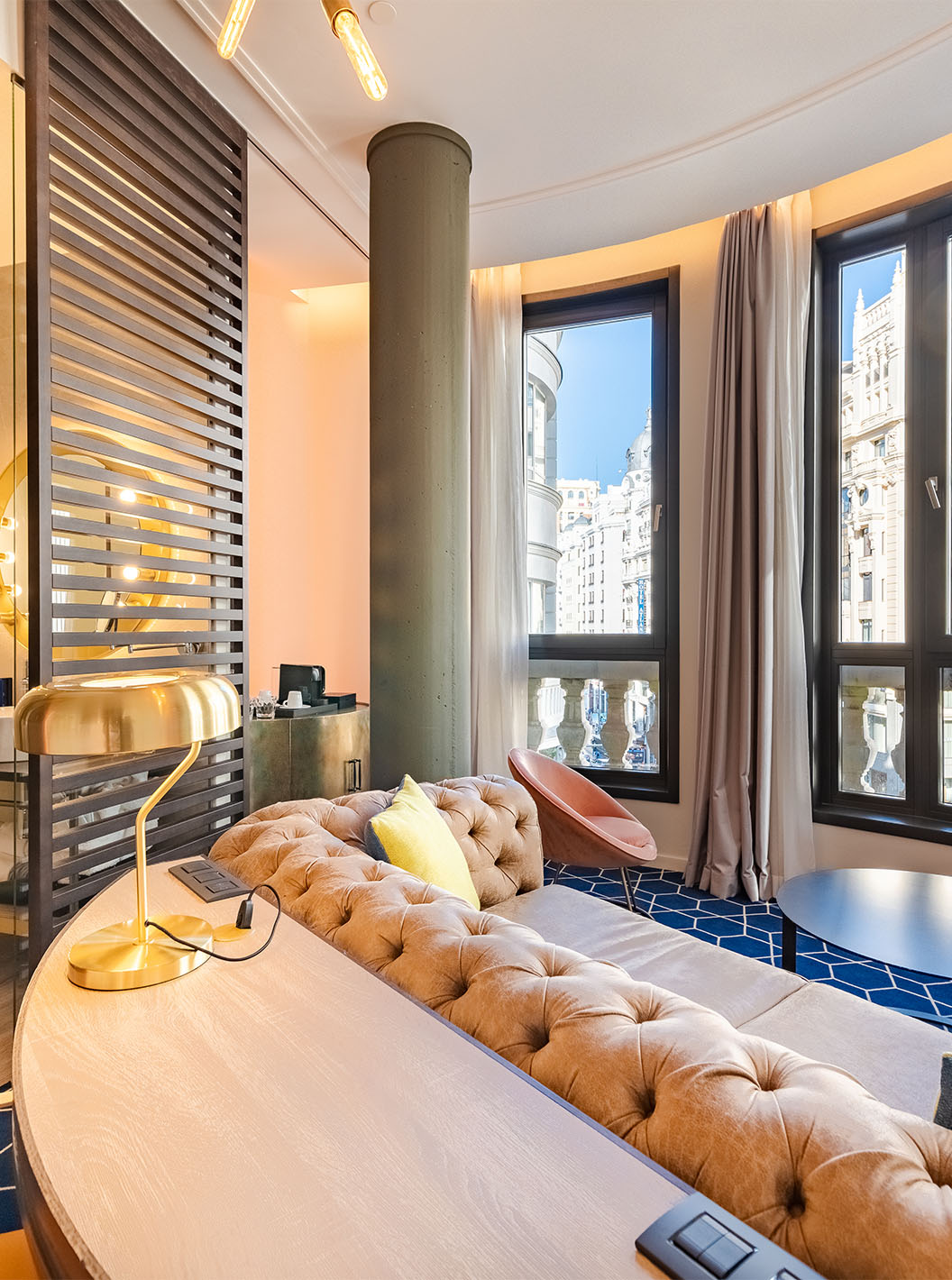 The Fantastic 7 Room at Pestana CR7 Gran Vía Madrid has a sofa with a coffee table and large windows facing nearby buildings