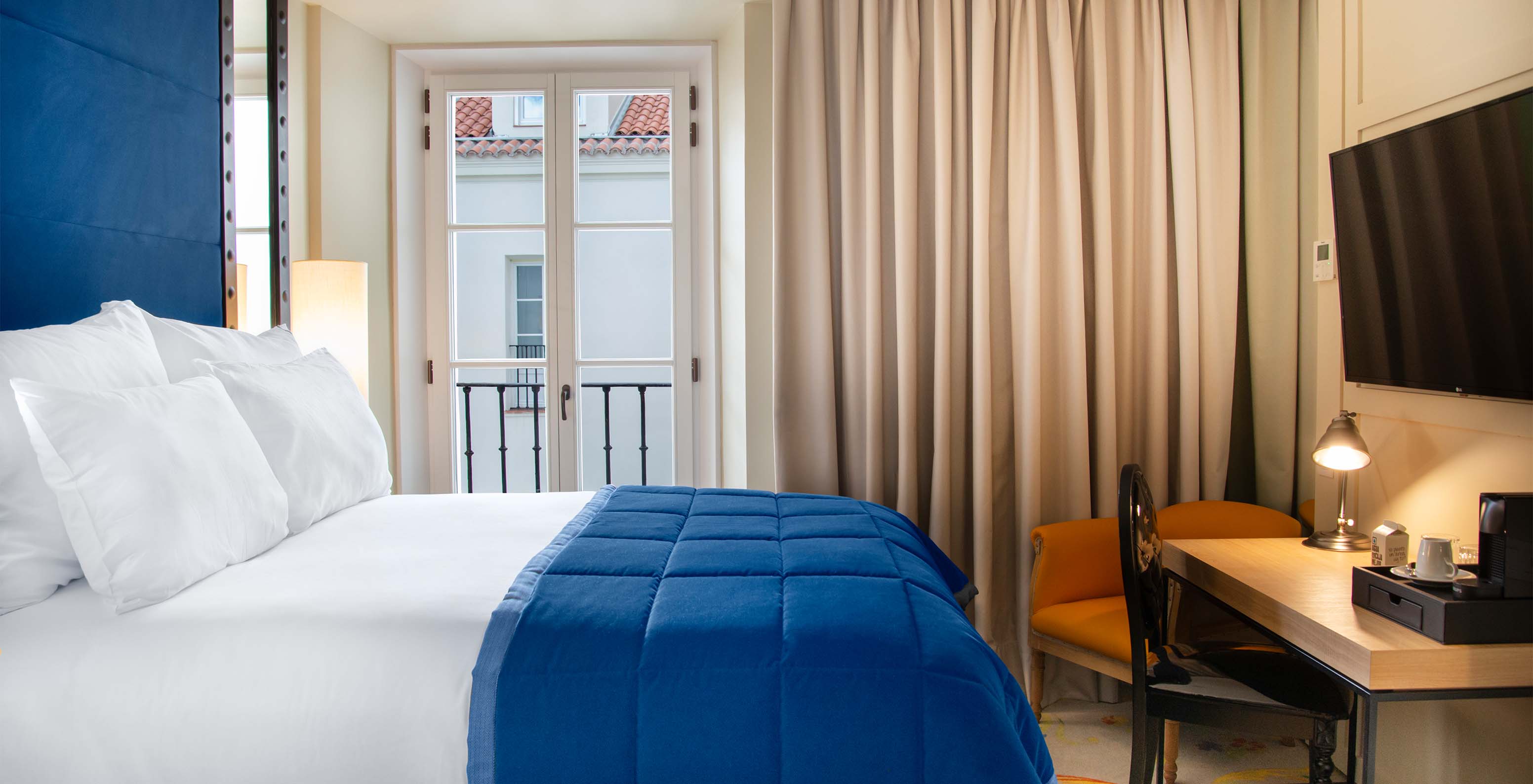 The Classic Room at Pestana Collection Plaza Mayor has a double bed, TV, desk and a window with curtains