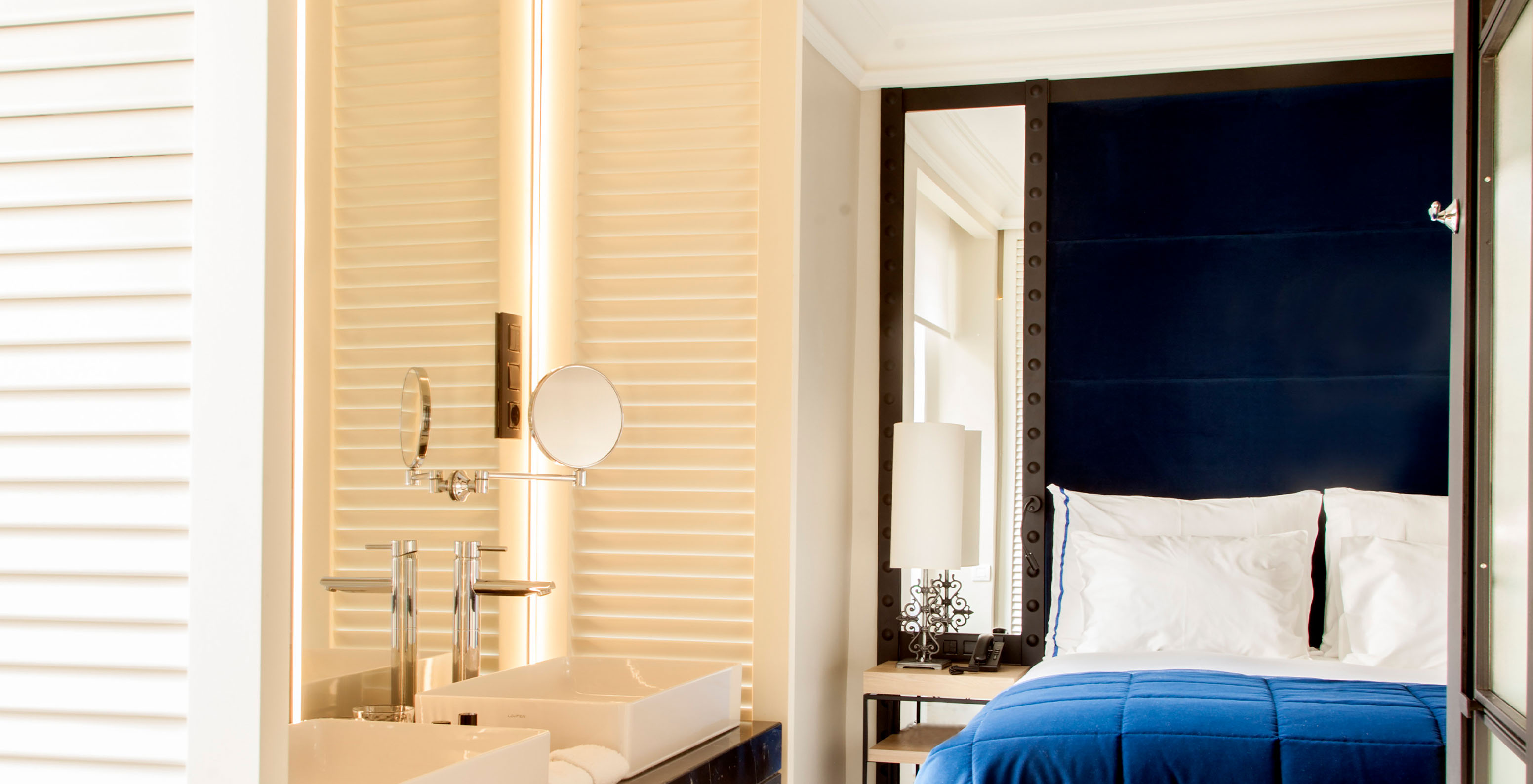 The Superior Room at Pestana Collection Plaza Mayor has a double bed with blue headboard with mirror and a sink