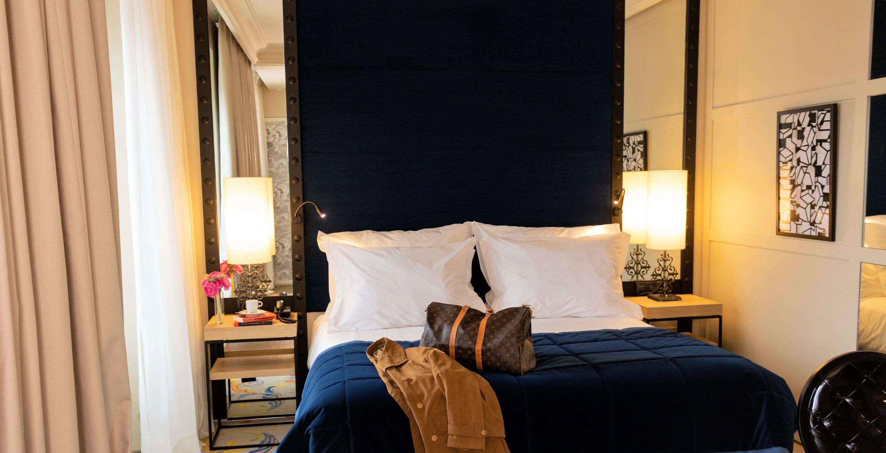 The Superior Plus Room at Pestana Collection Plaza Mayor has a double bed with a suitcase and a coat on the bed.