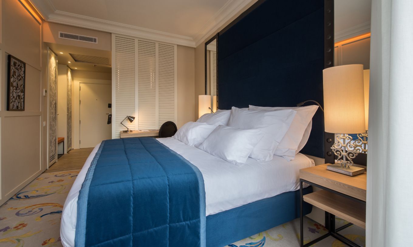 The Superior Plus Room at Pestana Plaza Mayor Madrid has a double bed with a blue bedspread and a rug.