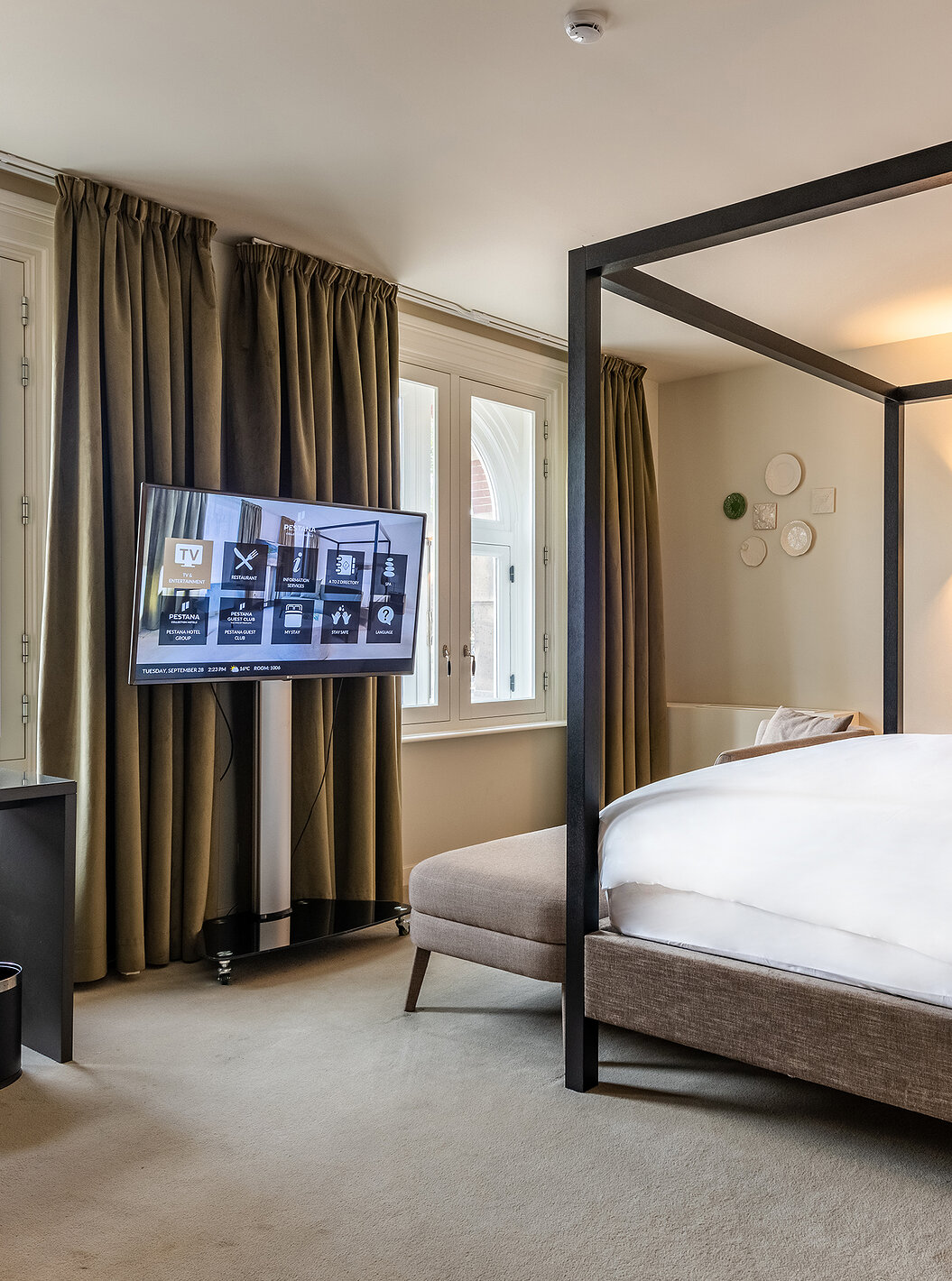 Premium Deluxe room at Pestana Amsterdam Riverside has a TV in front of the bed and a desk with chair