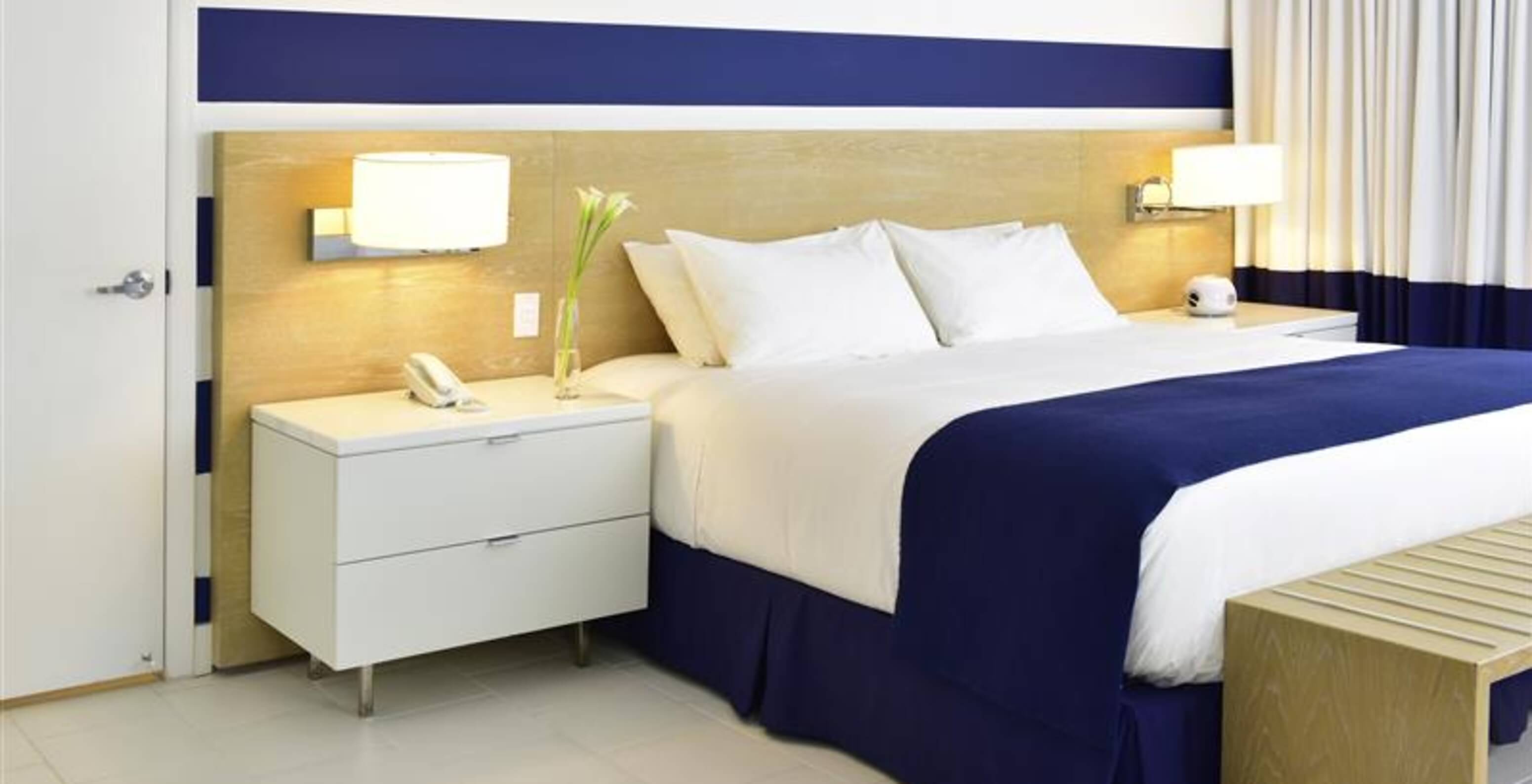 The Superior King at Pestana Miami South Beach has a double bed, bedside table and a lamp