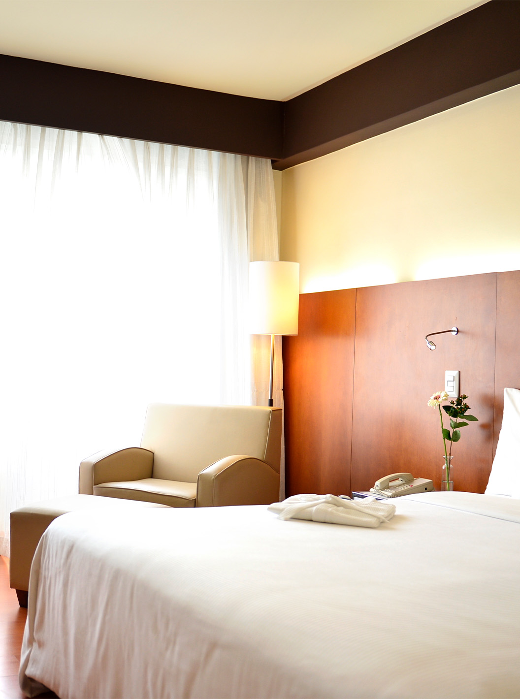 The Executive King Room at Pestana Caracas has a double bed with a wooden headboard and a window with curtains