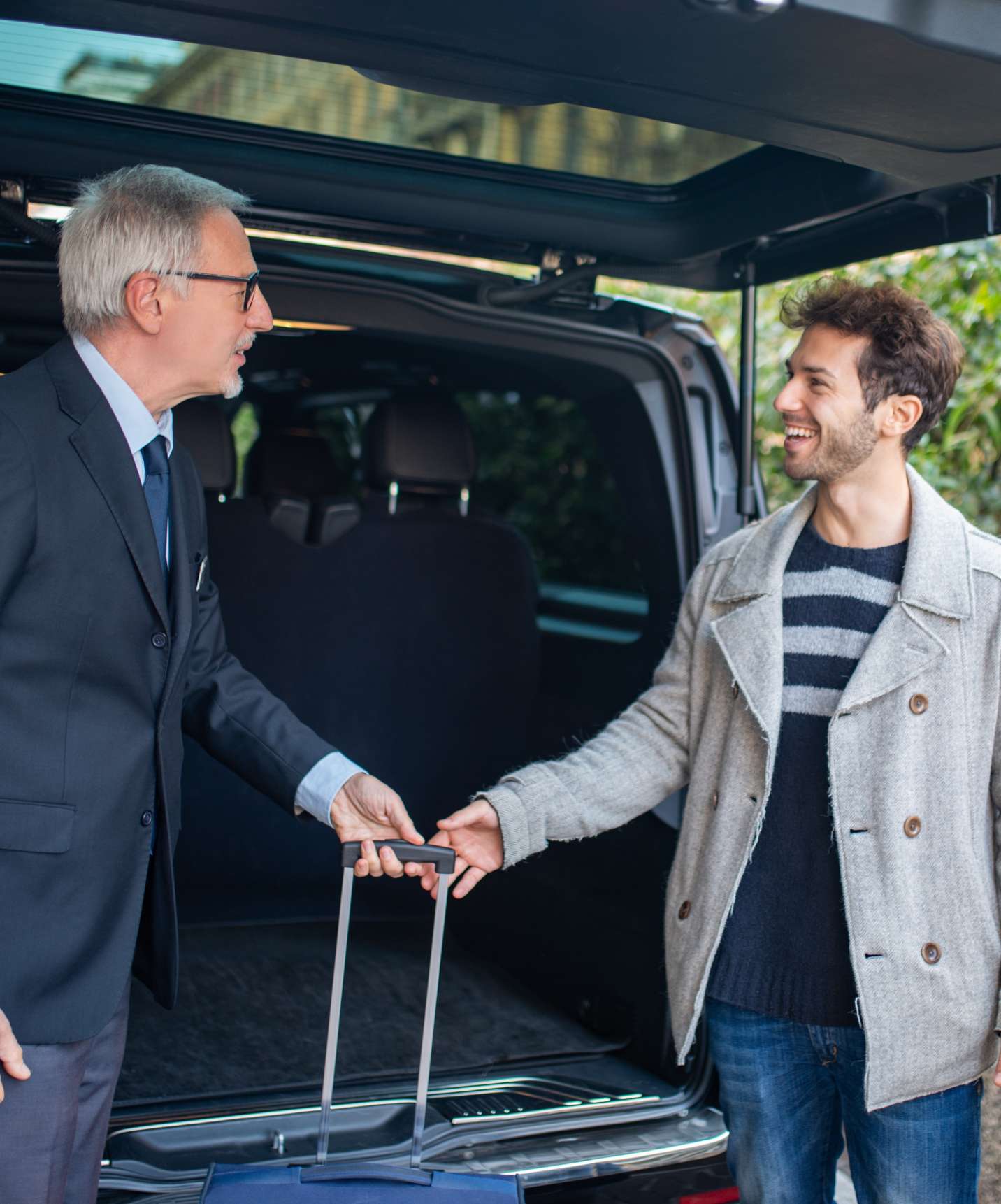 Driver taking luggage from the trunk and handing it to a couple arriving at Pestana Quinta Perestrello