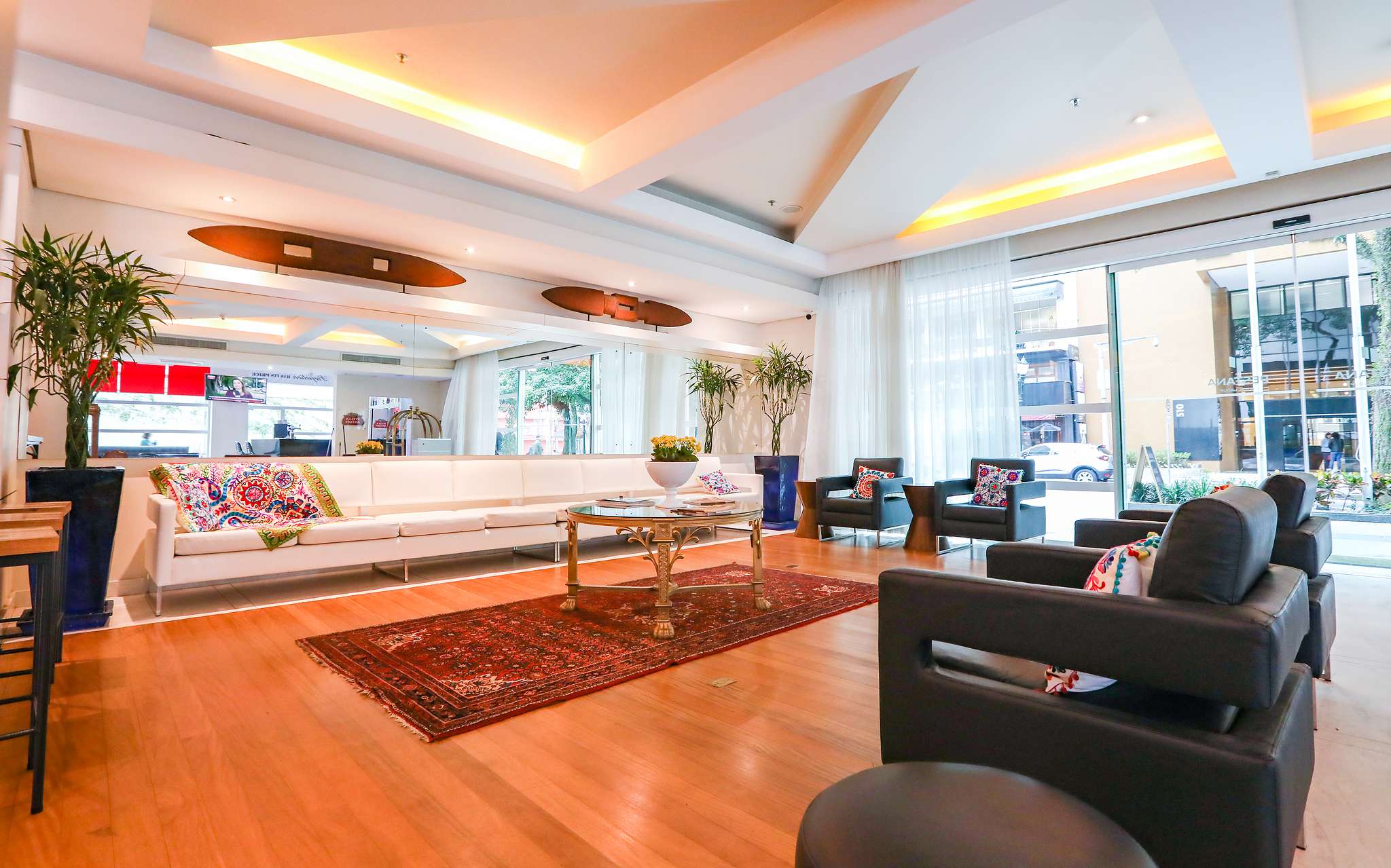 Entrada de Pestana Curitiba con 4 sillones y sofá blanco largo con almohadas coloridas y mesa de centro