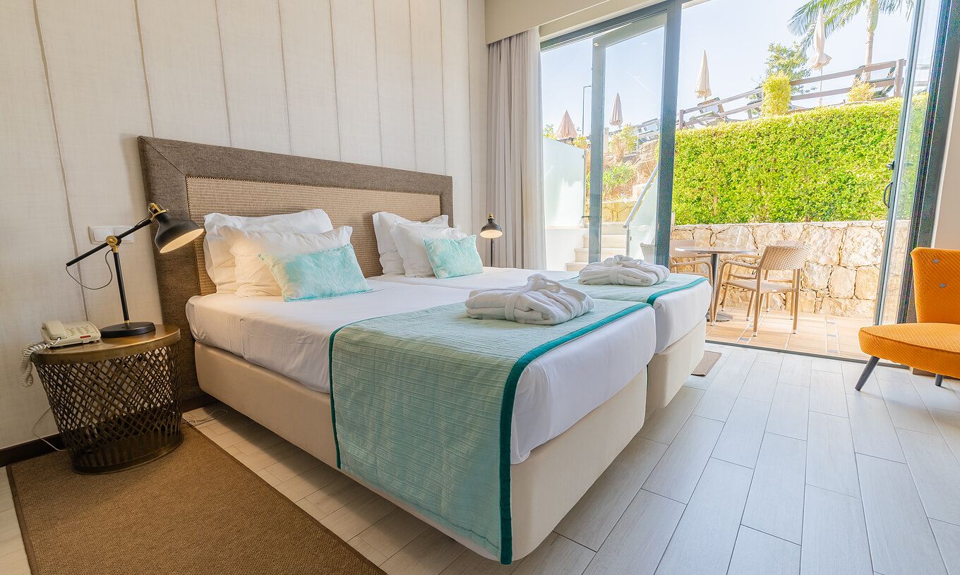 La Suite Garden del Pestana Alvor Park tiene dos camas, un sillón, cortinas y un balcón con mesa y sillas