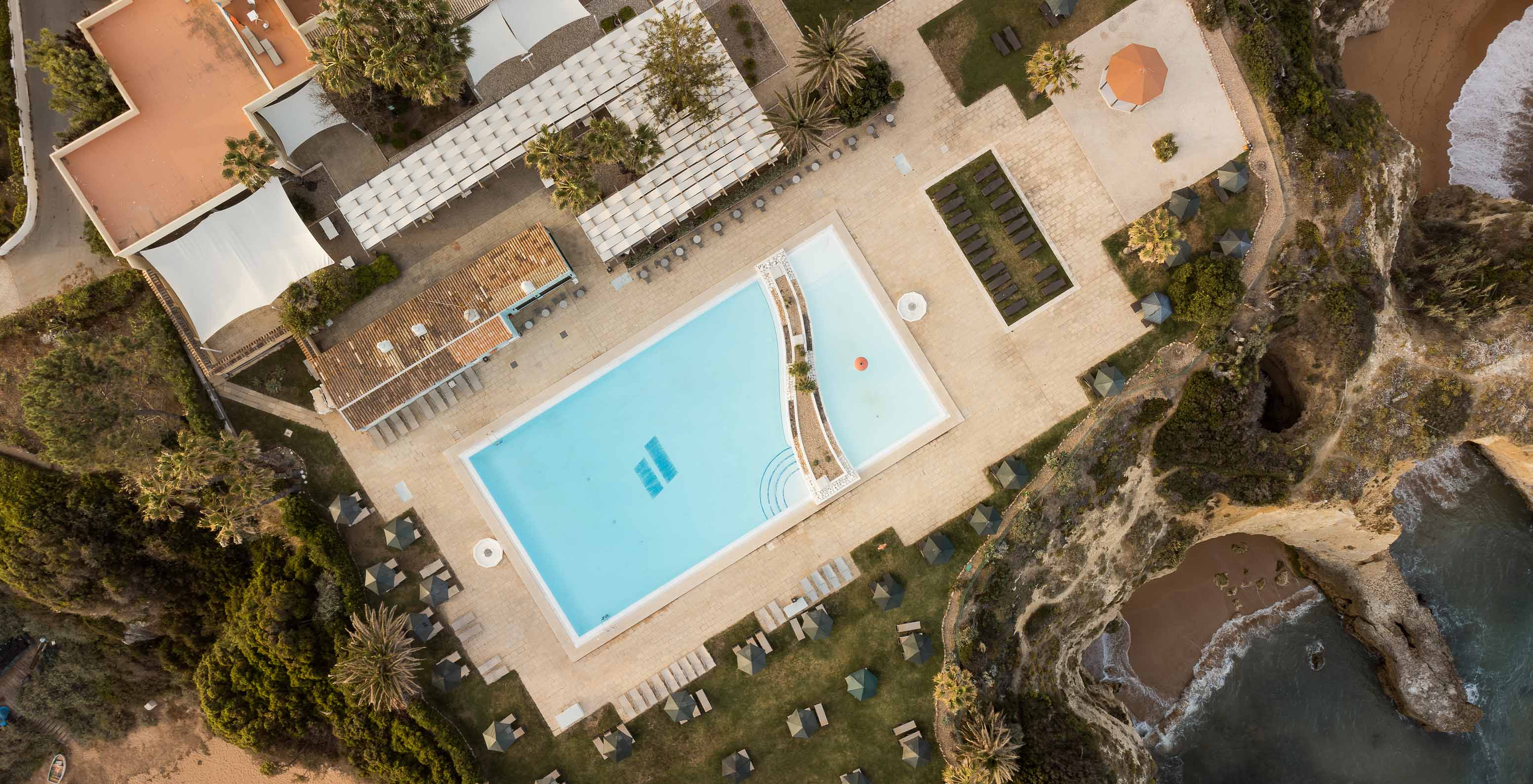 Vista de dron de la piscina exterior del Pestana Viking, con palmeras, tumbonas y vistas al mar