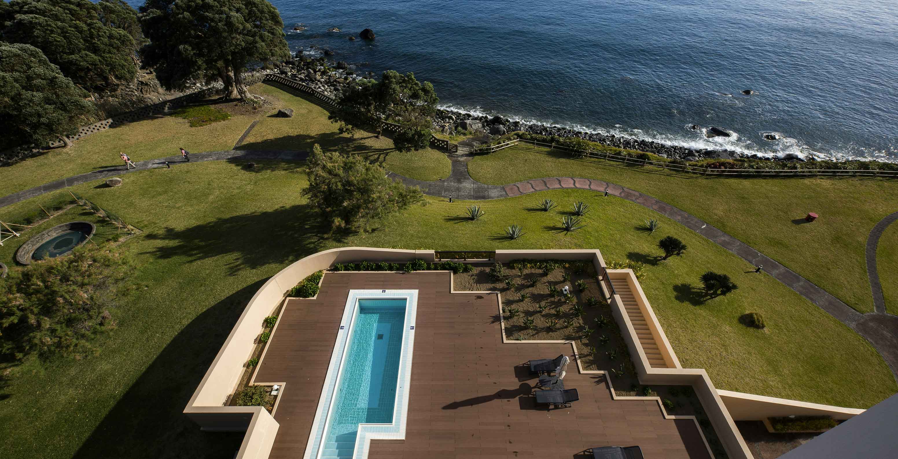 Piscina del Pestana Bahia Praia sobre tarima de madera con vistas al mar y zona verde alrededor