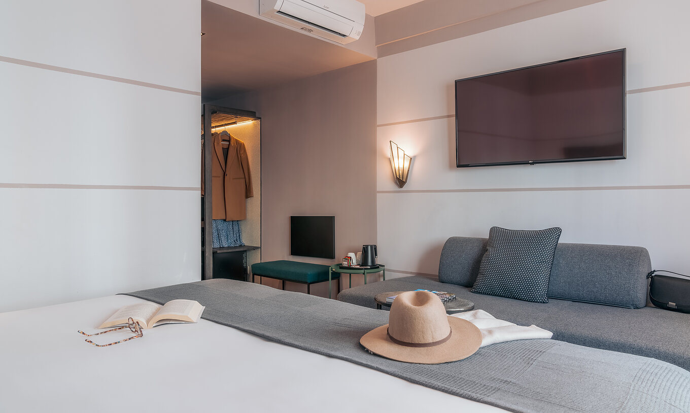 El Double Classic del Pestana Lisboa Vintage tiene una cama matrimonial con una manta gris, un sofá gris y un televisor