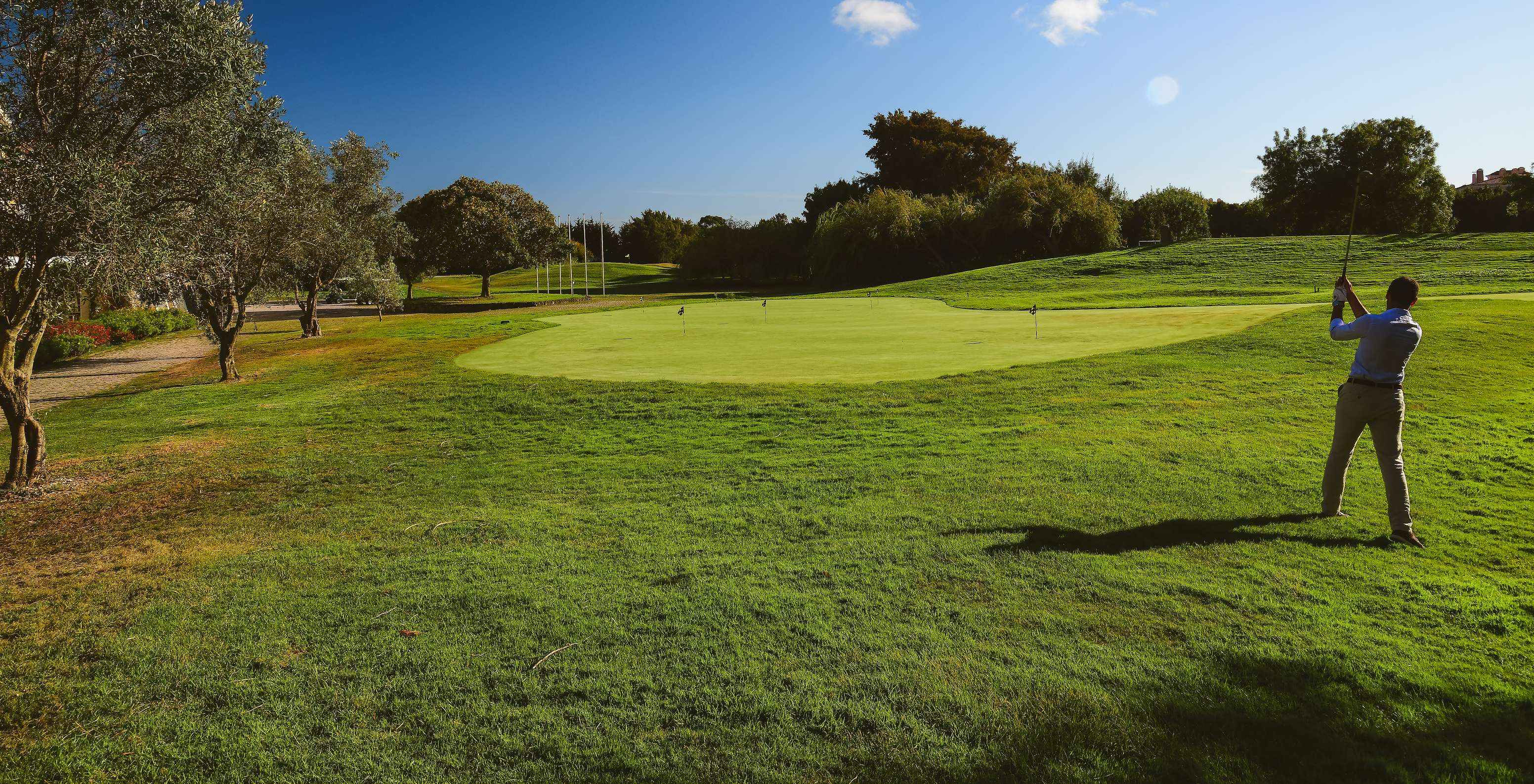 Hombre haciendo un golpe en el campo de golf en un día soleado y cielo azul en el Pestana Sintra Golf Hotel