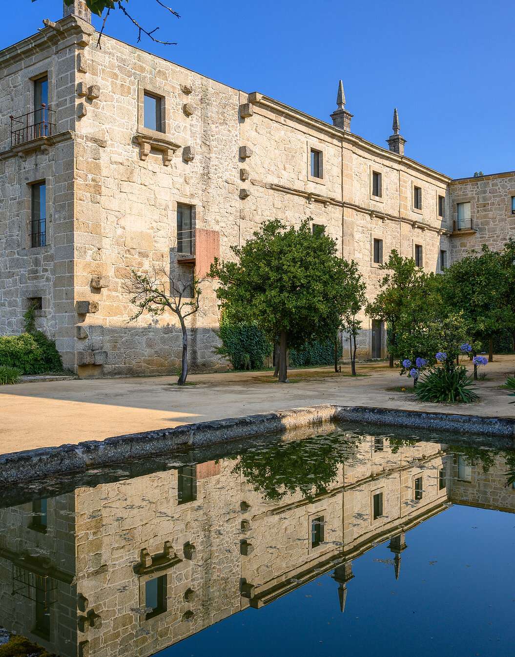 Vista exterior del edificio de Pousada Mosteiro Amares, un hotel histórico en Gerês, en piedra con un lago enfrente