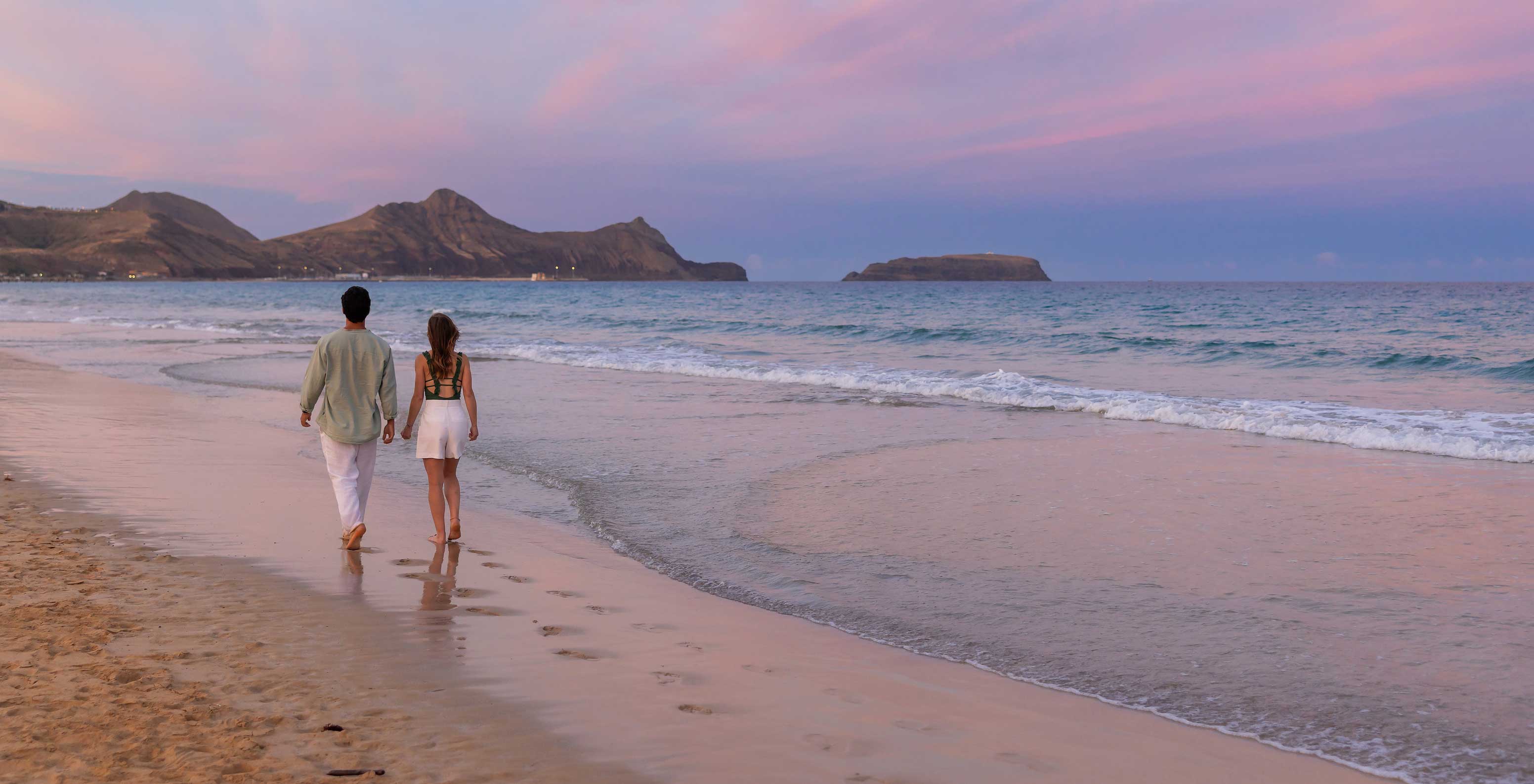 Una pareja paseando junto al mar en la playa de la isla de Porto Santo, frente al Pestana Porto Santo All Inclusive
