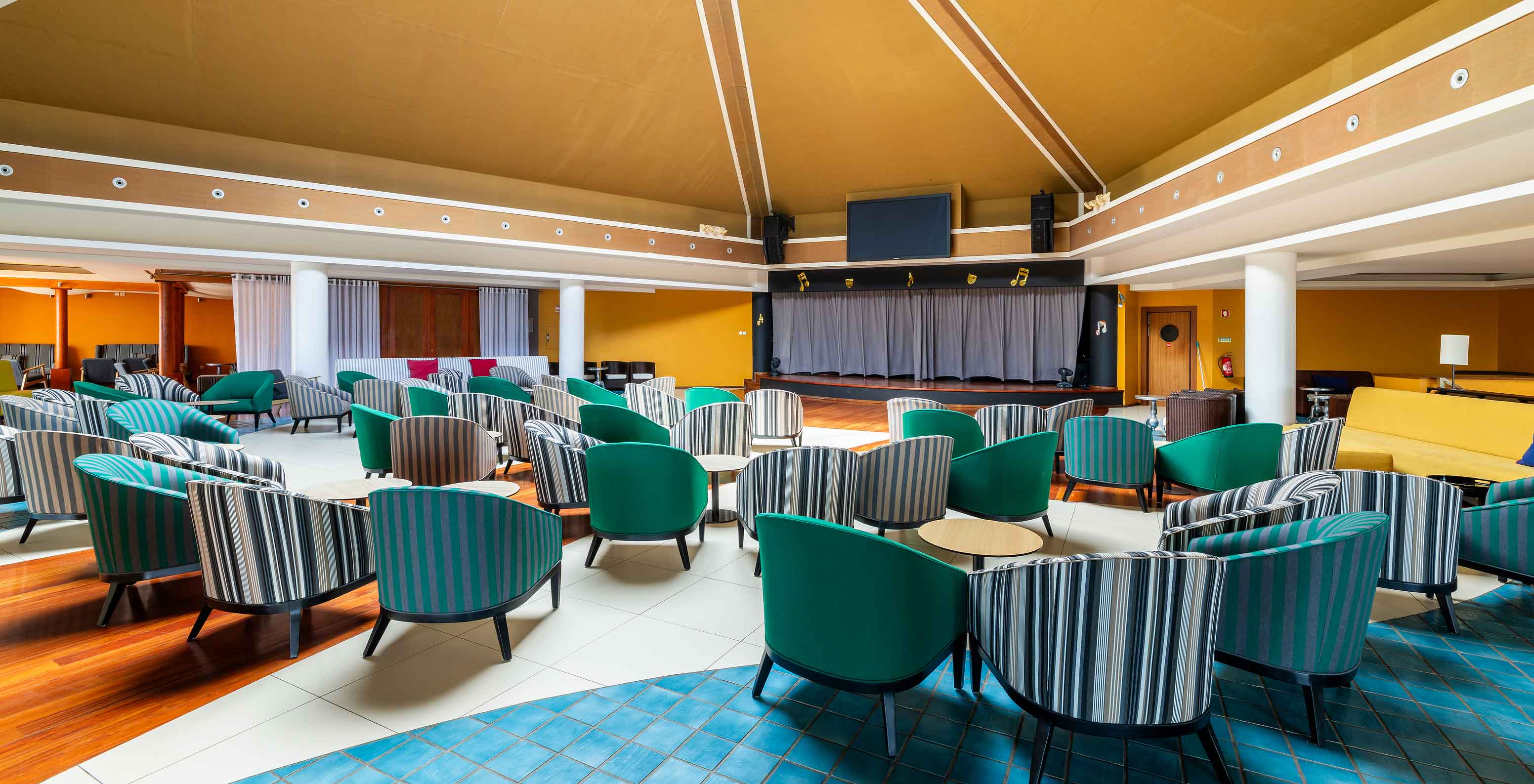 El bar Sunset, del Resort de 5 estrellas en Porto Santo, tiene un espacio amplio con paredes amarillas y sillas verdes.