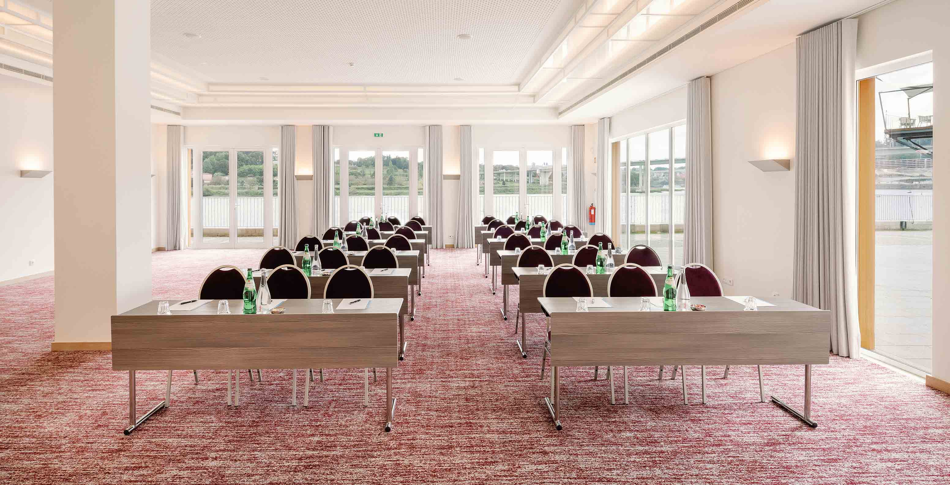 Sala Douro V con mesas sillas y grandes ventanas en el Pestana Douro Riverside Hotel con piscina frente al río Duero