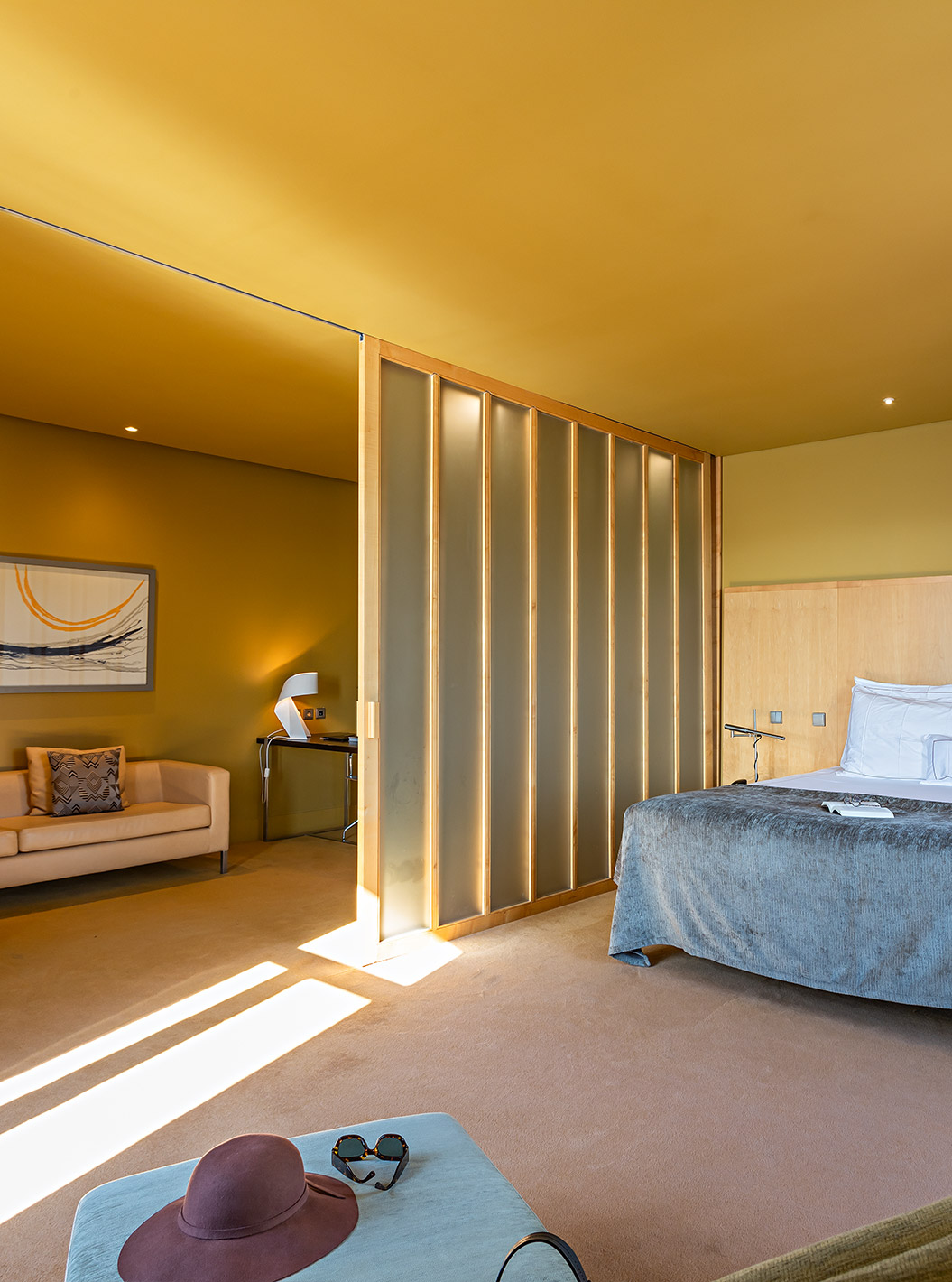 La Standard Suite tiene una cama doble grande con una manta gris y un sofá