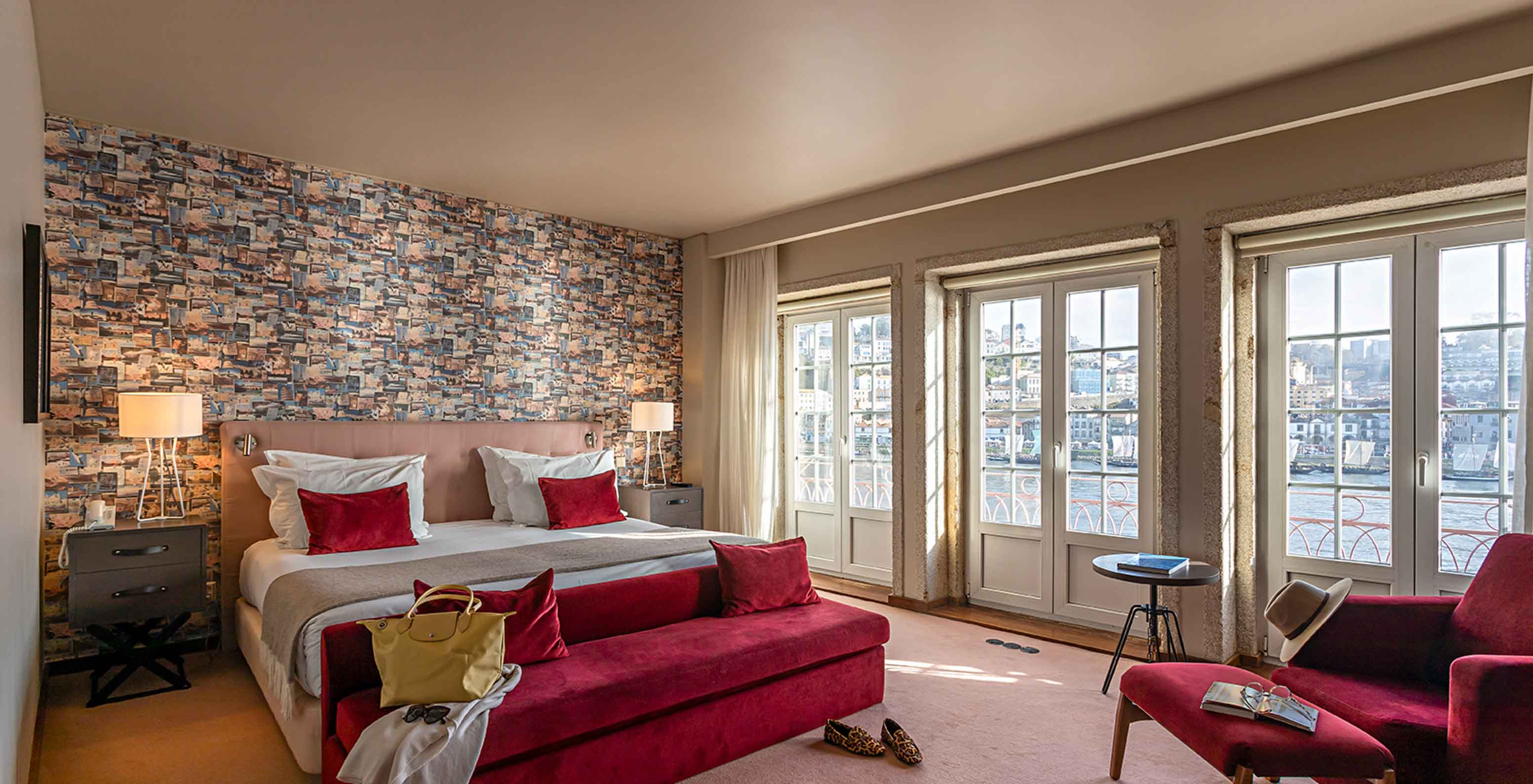La Suite Grand View del Pestana Vintage Porto tiene una cama doble, un sofá rojo y ventanas con vista a Oporto