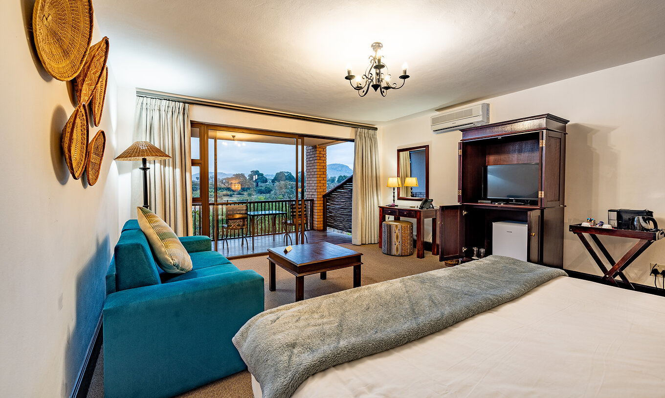 El Premium Room del Pestana Kruger Lodge tiene una zona de estar con sofá, televisor y decoración típica africana