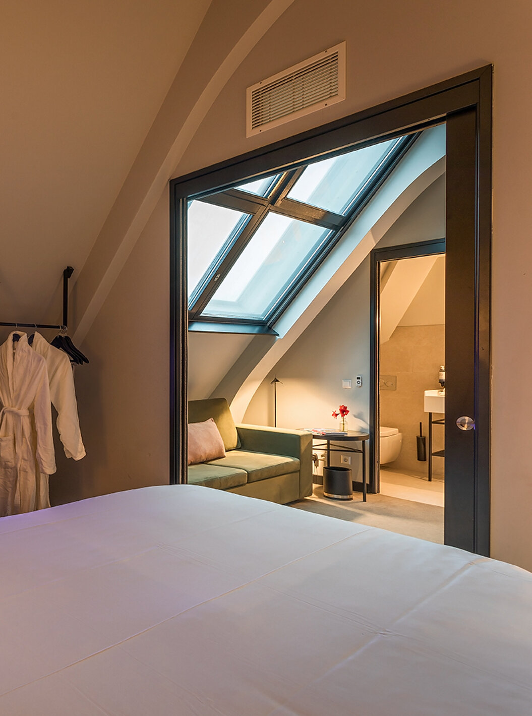 El cuarto Loft del Pestana Amsterdam Riverside tiene un sofá verde, mesa de centro y dos albornoces