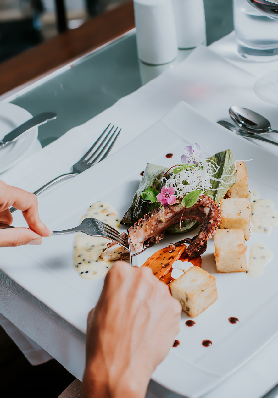 Plato blanco con pulpo y maíz frito, durante una comida en un hotel de Pestana Hotels and Resorts