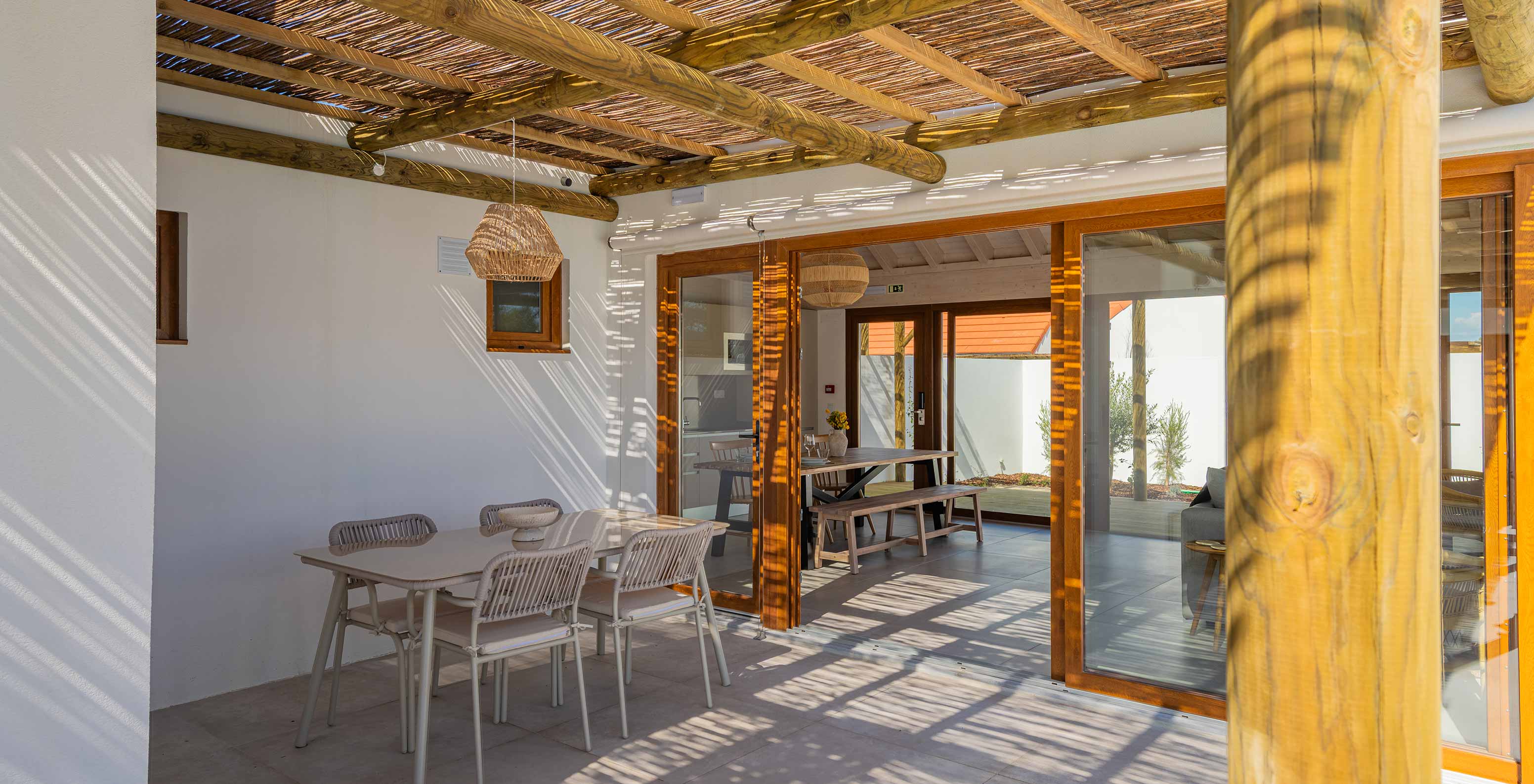 De Premium Villa bij Pestana Comporta Village Residences heeft een overdekte patio met een tafel die leidt naar het interieur