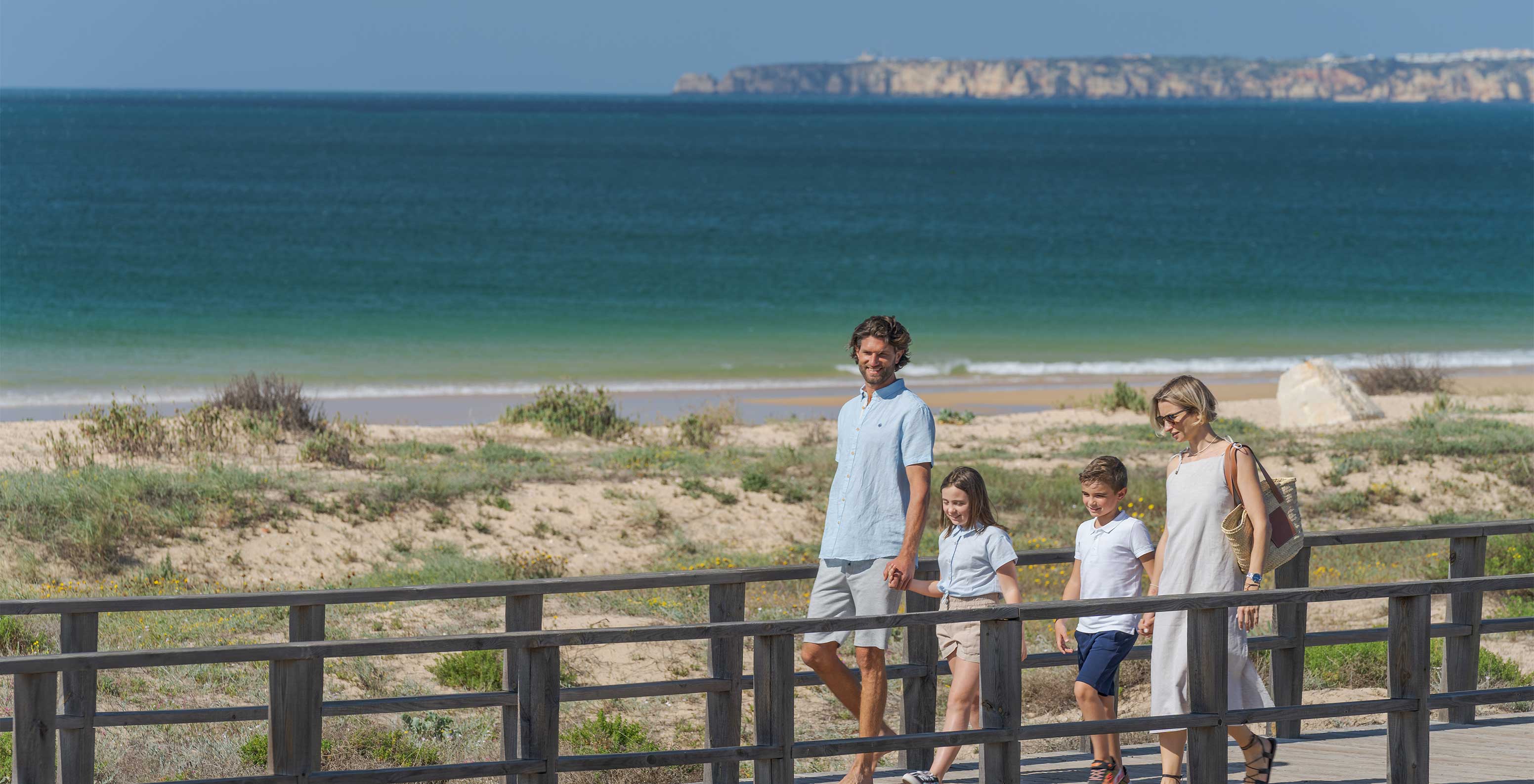 Glimlachende familie wandelt op de promenade bij het strand van Alvor in de Algarve
