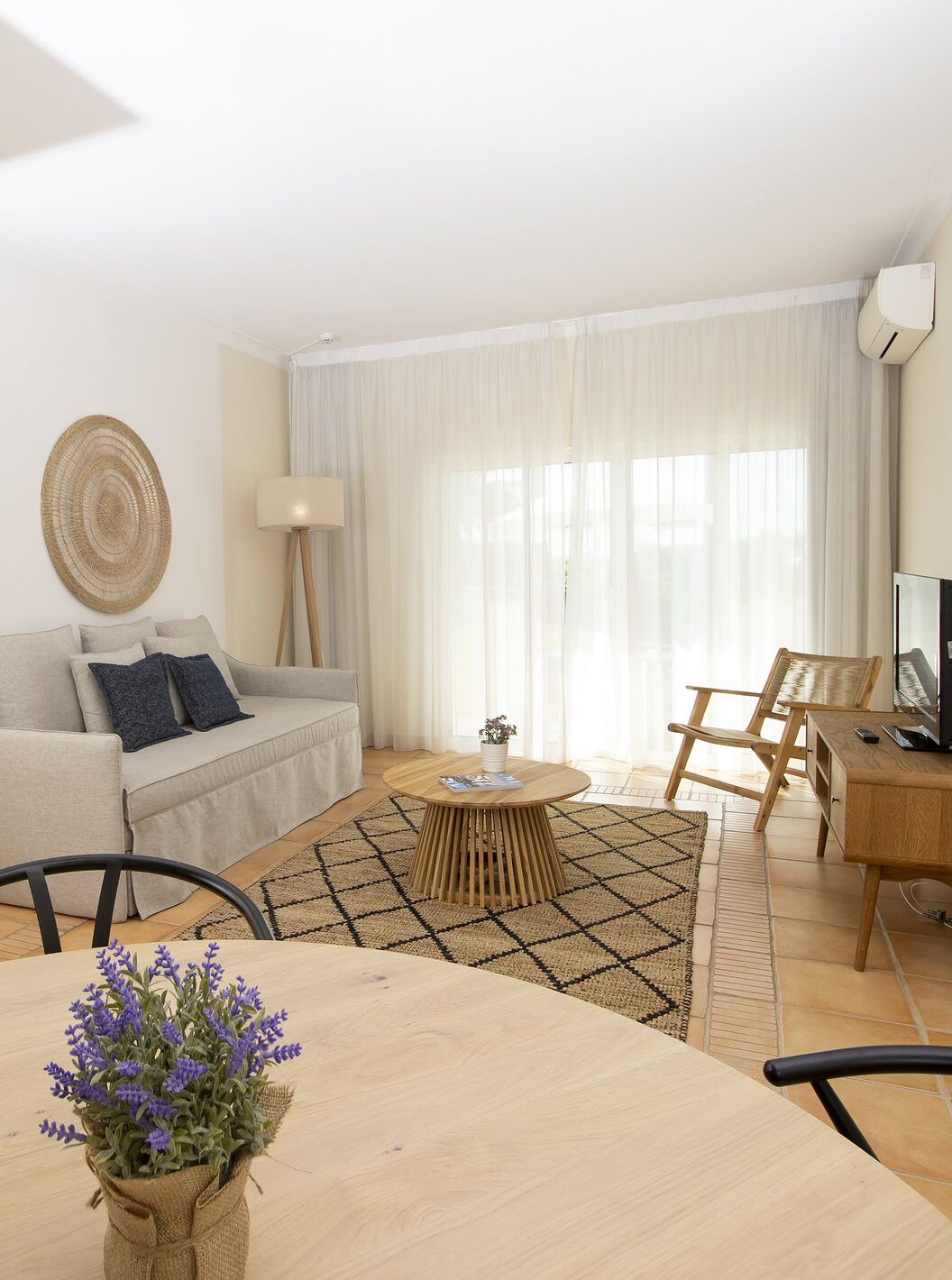 Het Appartement T2 Superior van Pestana Palm Gardens heeft een kamer met ronde tafel, bank, televisie en raam naar de tuin