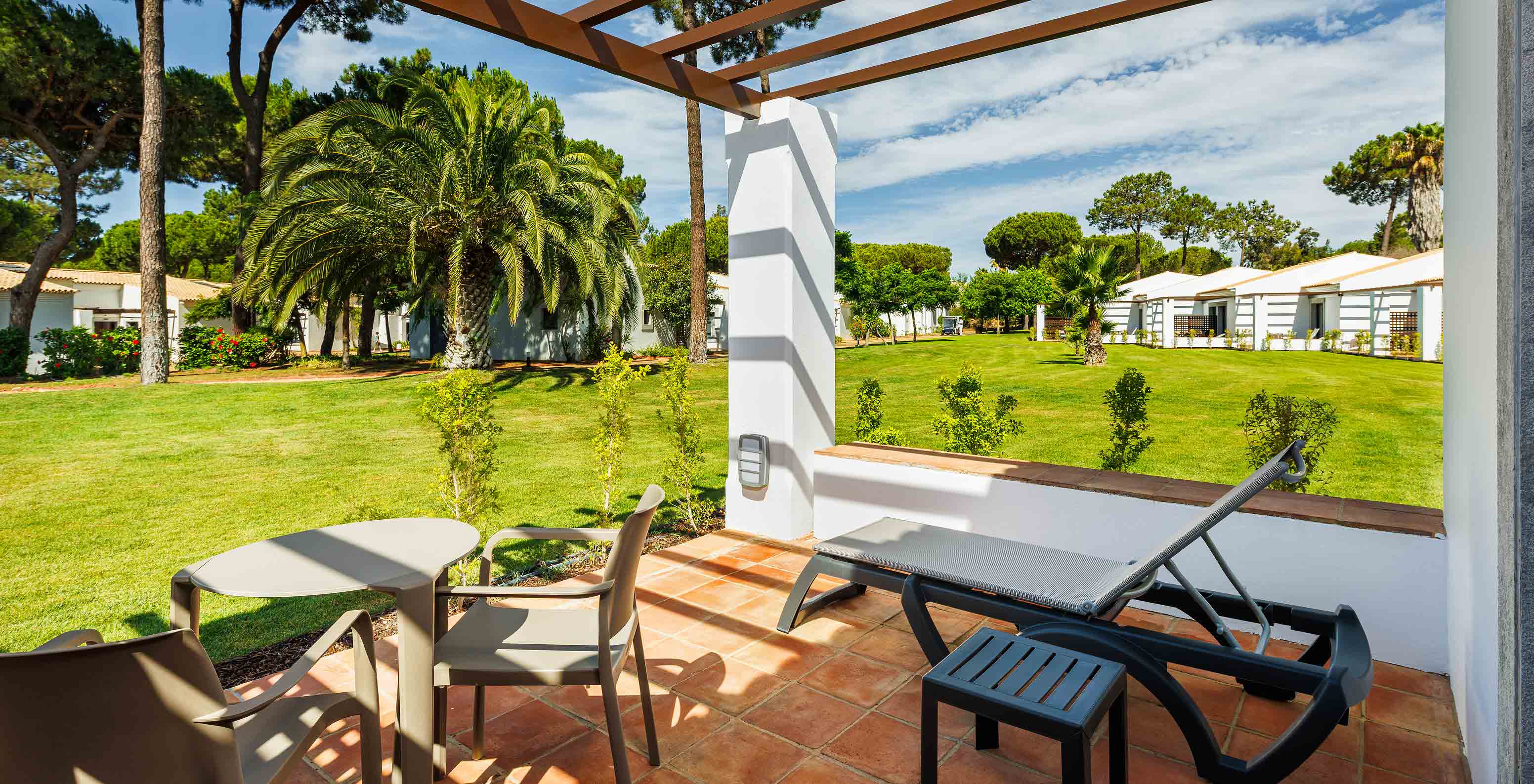 De Family Garden View bij Pestana Vila Sol - Vilamoura heeft balkon met ligstoel, tafel en uitzicht op de tuin