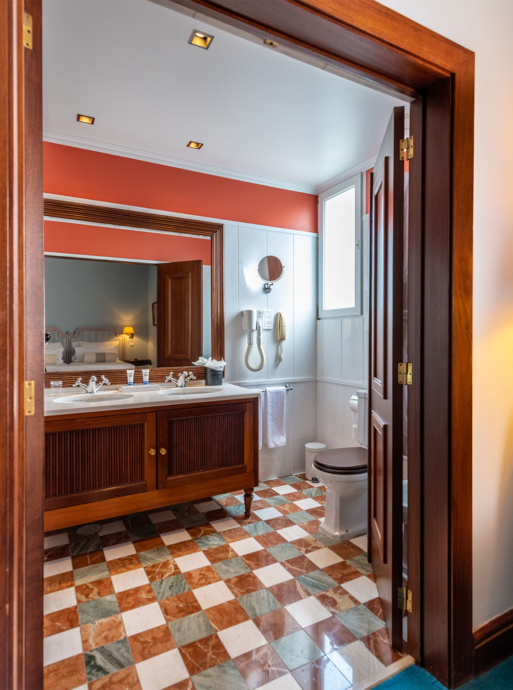 De Deluxe van Pestana Palace Lisboa heeft een badkamer met twee wastafels in een houten meubel, spiegel, toilet
