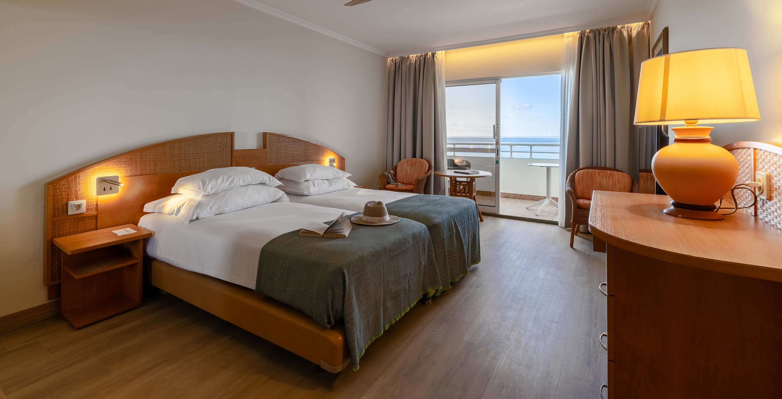 De Classic Sea View van het Pestana Ocean Bay All Inclusive heeft een tweepersoonsbed, een tv, twee stoelen en een balkon