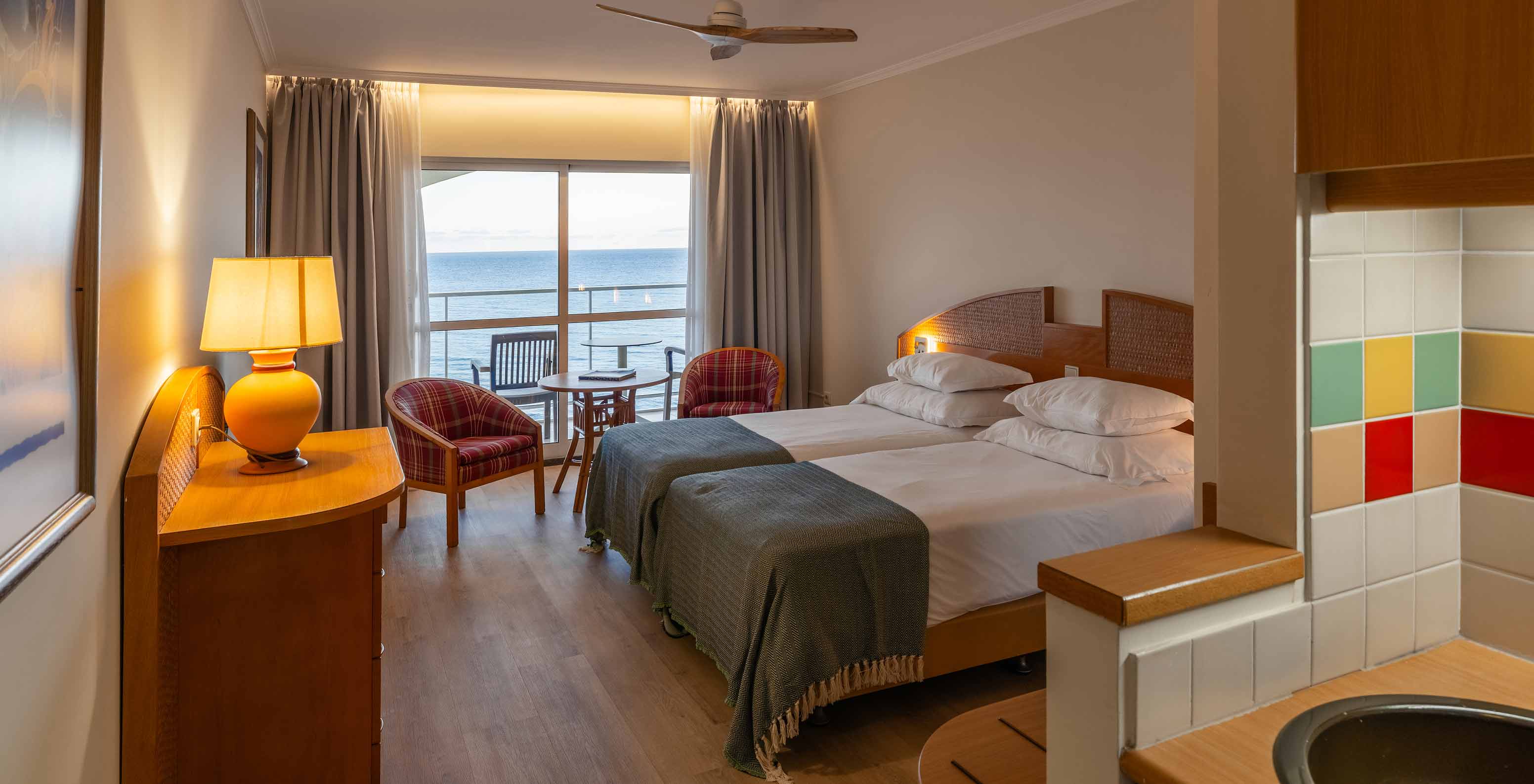 De Superior Sea View van het Pestana Ocean Bay All Inclusive heeft een tweepersoonsbed, twee fauteuils en een balkon