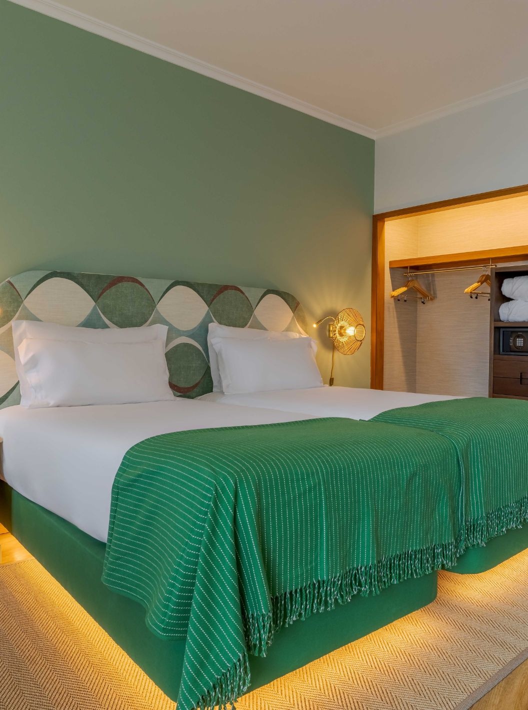 De Superior Zijdelings Zeezicht kamer van Pestana Vila Lido Madeira heeft een tweepersoonsbed met een groen hoofdeinde en een kledingkast.