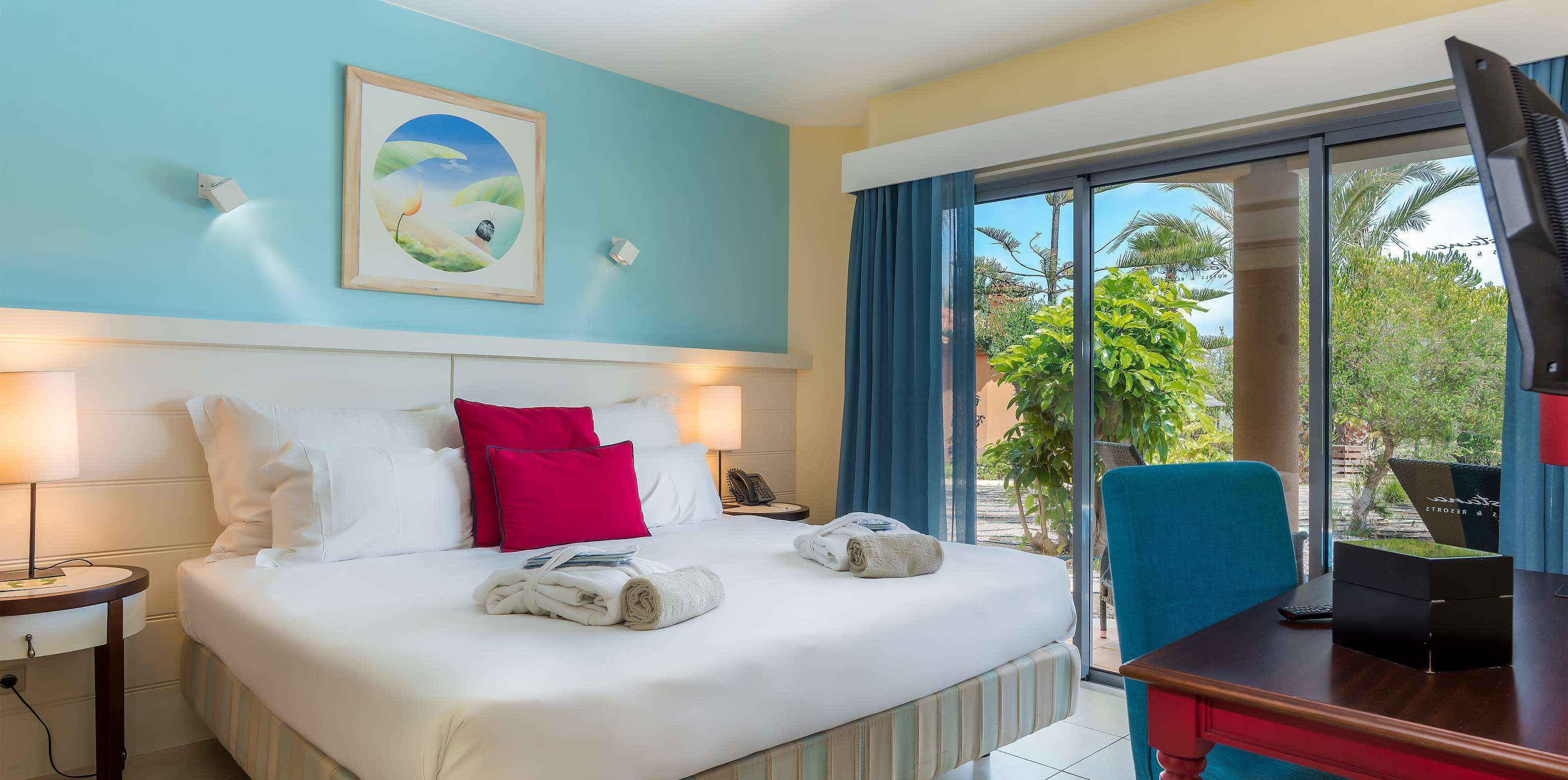 De Pool Villa van Pestana Porto Santo All Inclusive heeft een slaapkamer met tweepersoonsbed en een groot raam in blauwtinten