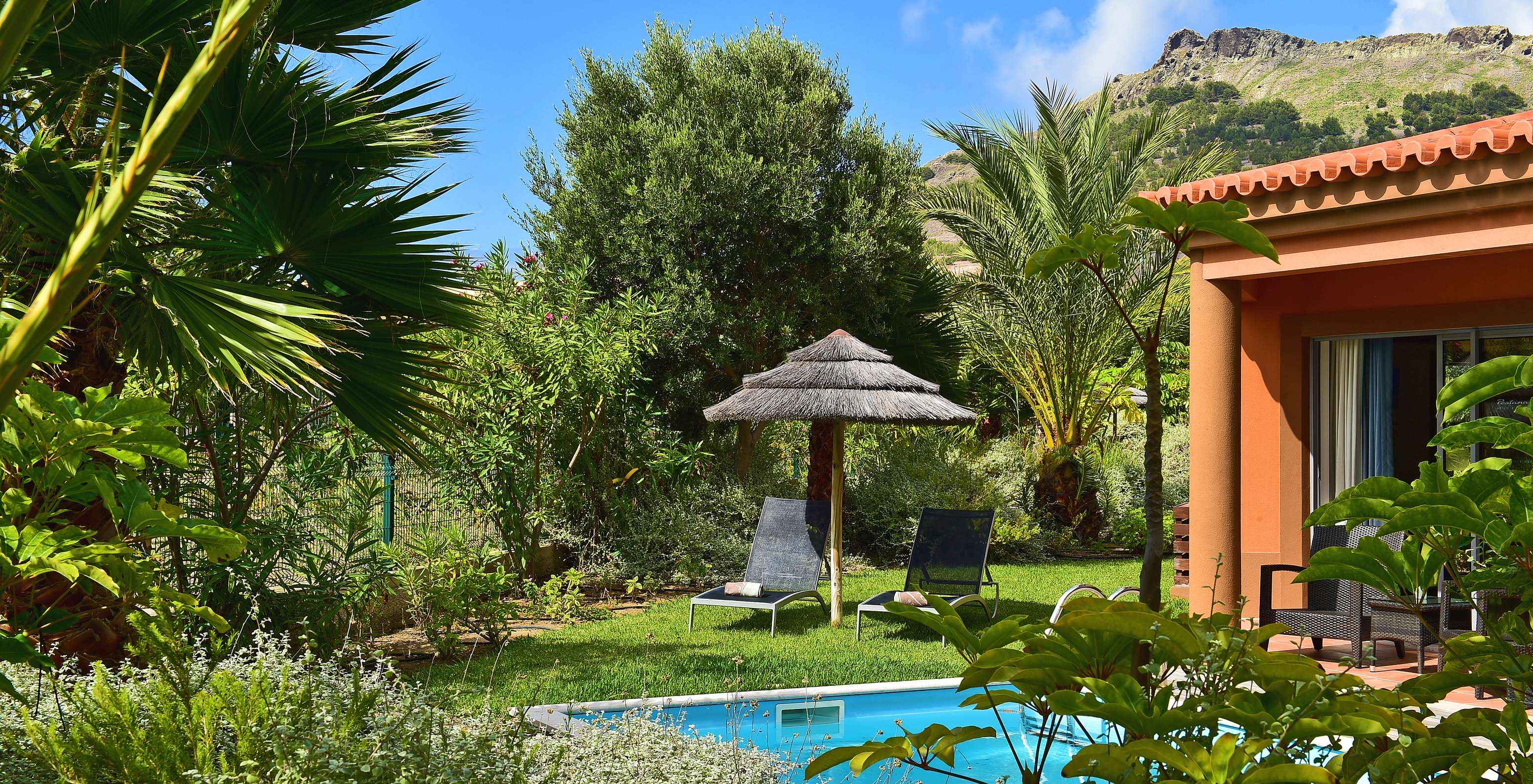De Pool Villa van Pestana Porto Santo All Inclusive heeft een privézwembad ligstoelen en een parasol