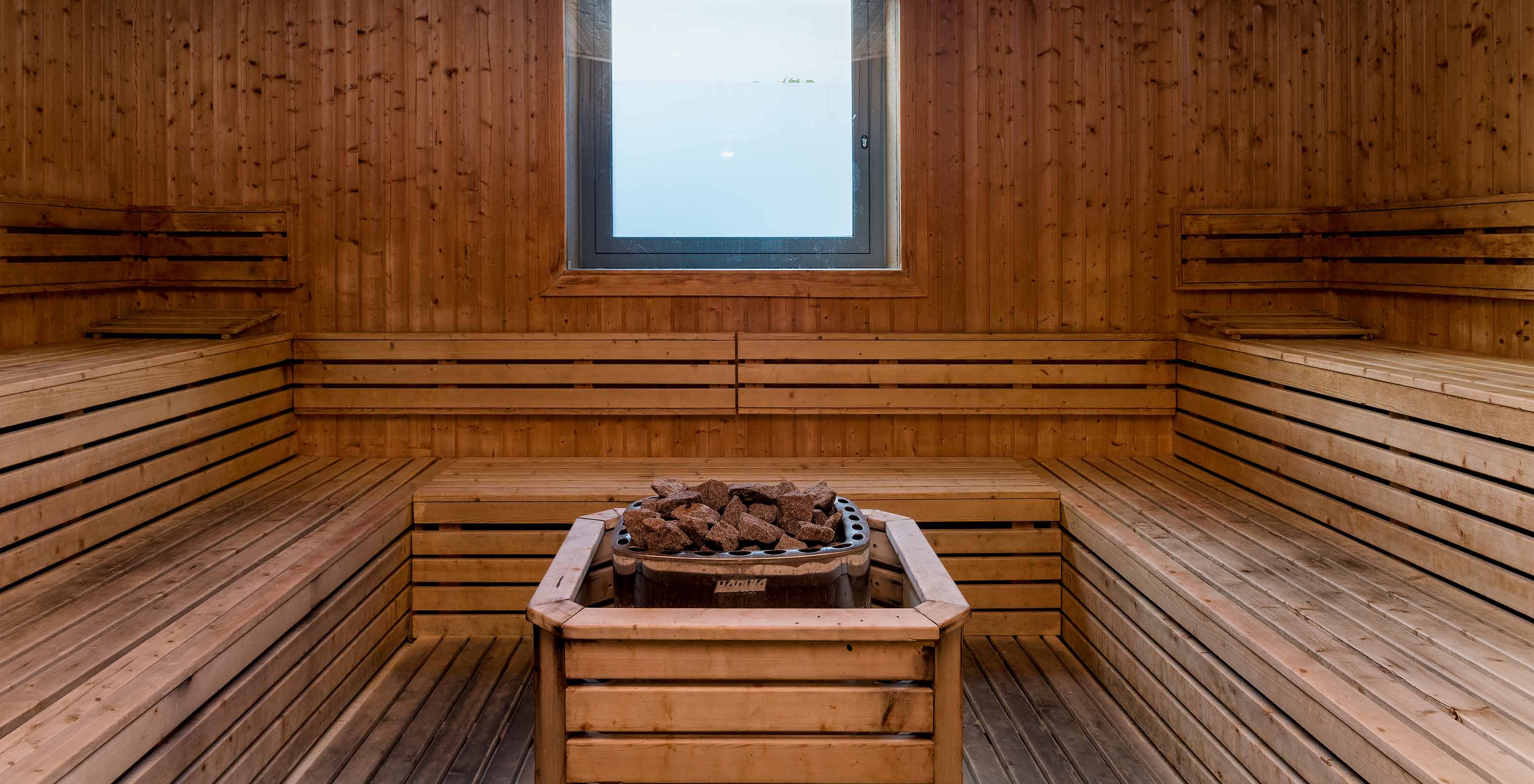 Interieur lichte houten sauna Pestana Porto Santo, hete stenen midden, klein raam
