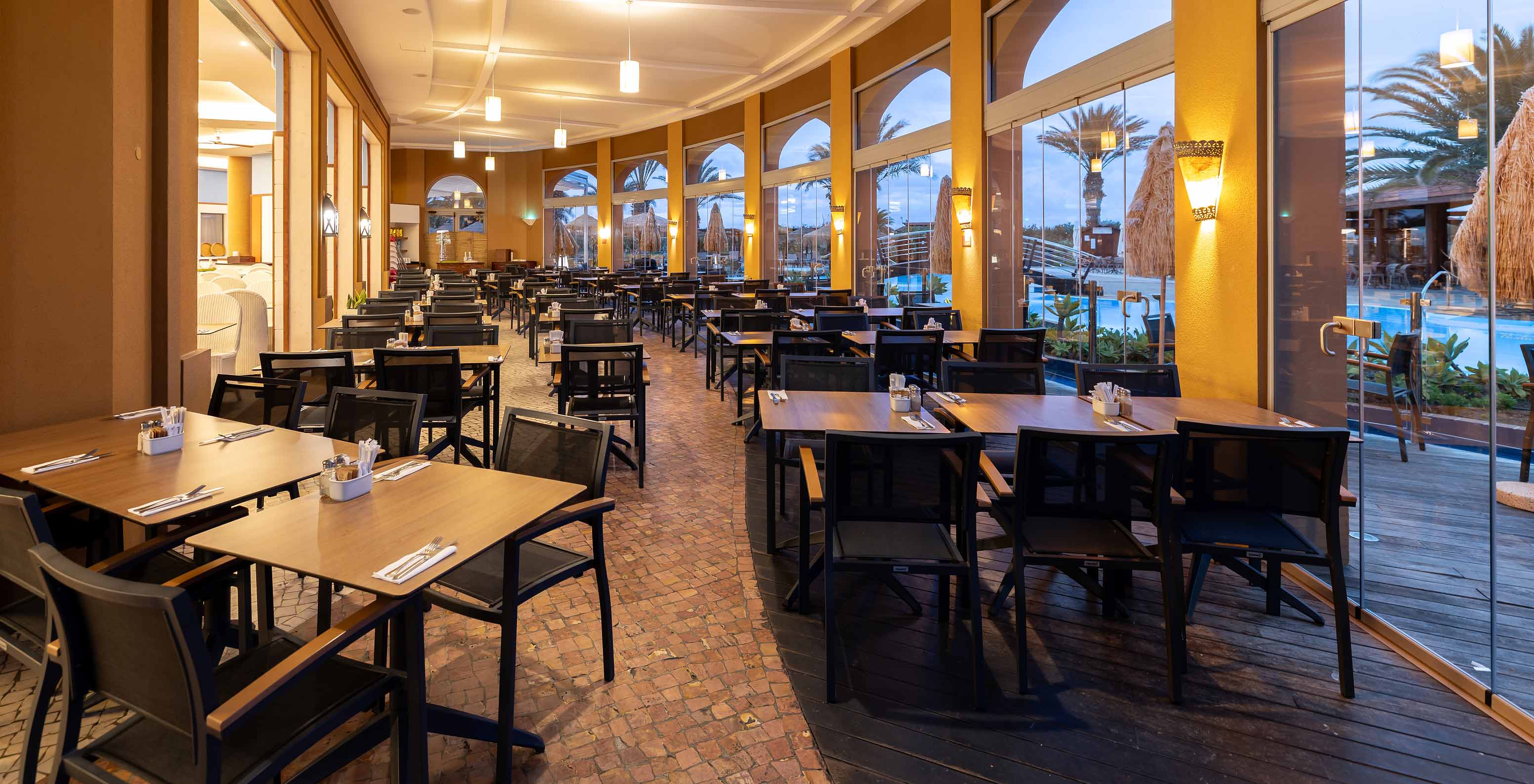 Restaurant Marés van het 5-sterrenresort op Porto Santo heeft een buitenruimte met vierkante tafels en stoelen.