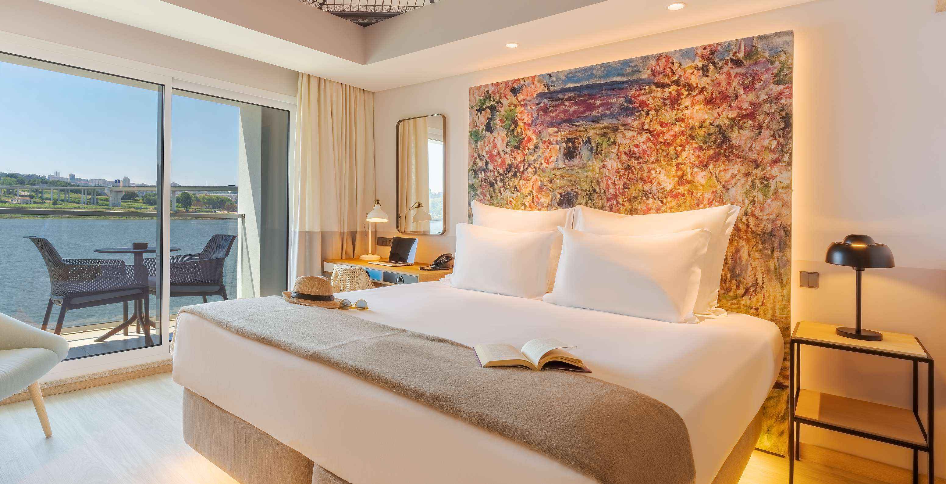 De Deluxe River View kamer van Pestana Douro Riverside heeft een tweepersoonsbed, nachtkastje en balkon met uitzicht