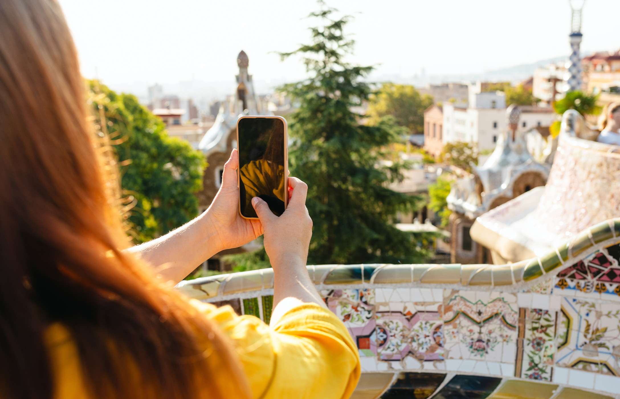 Persoon die het uitzicht op Barcelona fotografeert in het beroemde Park Güell met hun mobiele telefoon