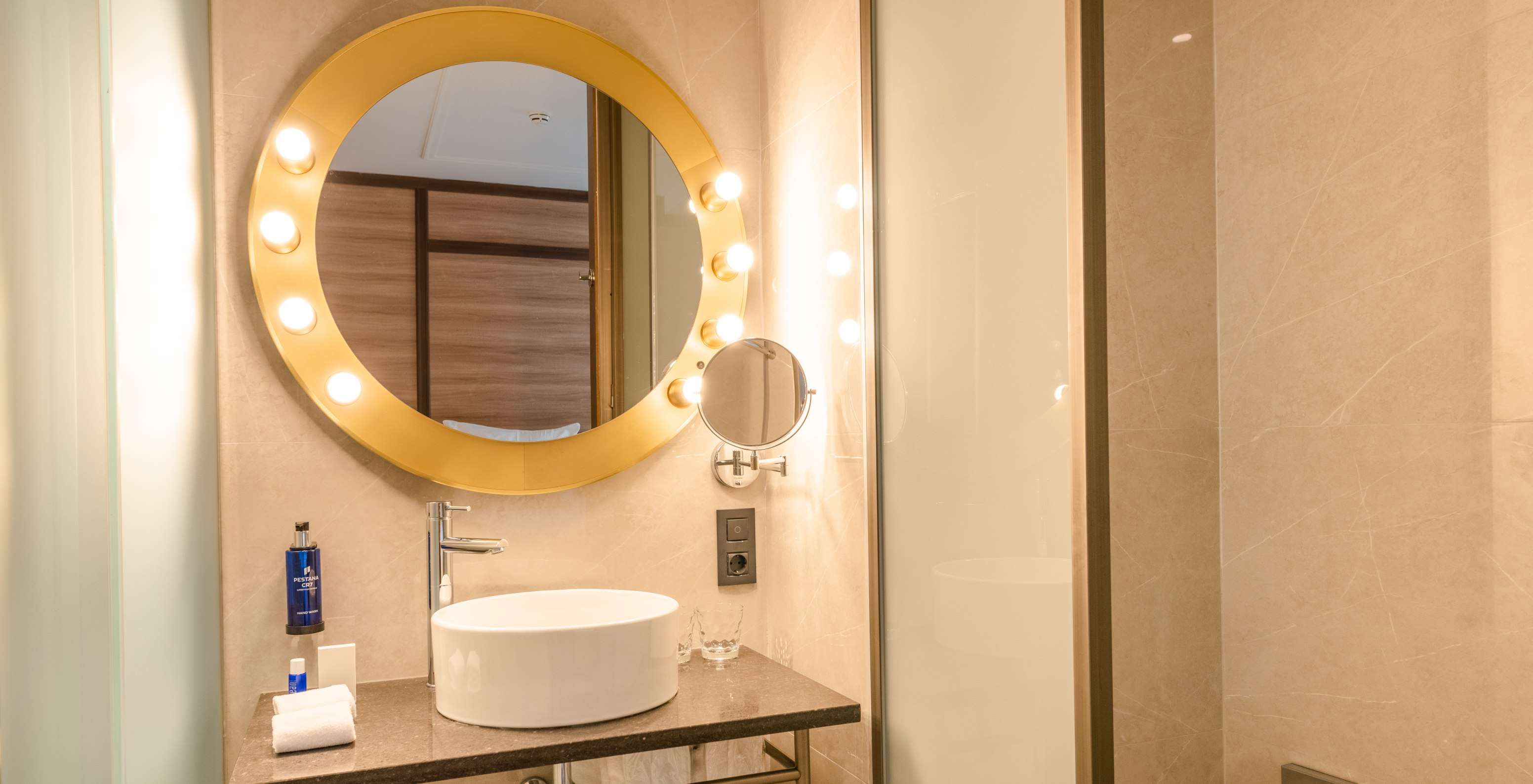 De Gezellige Kamer van Pestana CR7 Gran Vía Madrid heeft een badkamer met een ronde spiegel met lampen