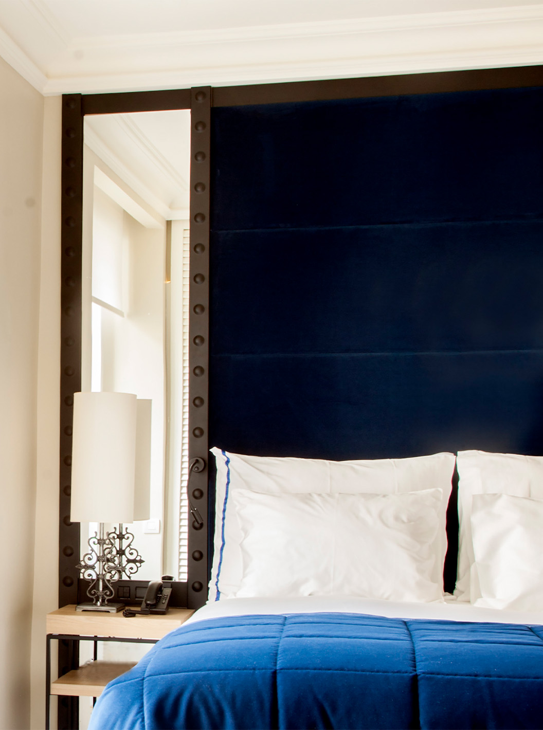 De Superior kamer van Pestana Plaza Mayor Madrid heeft een tweepersoonsbed met blauwe hoofdeinde met spiegel en een wastafel