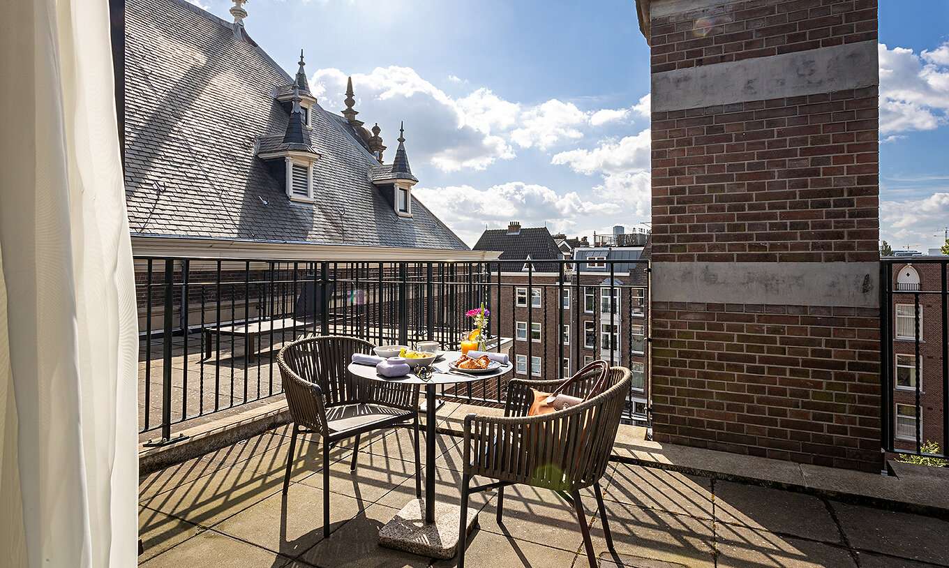 De Executive Terrace kamer van Pestana Amsterdam Riverside heeft een balkon met een tafel en twee stoelen