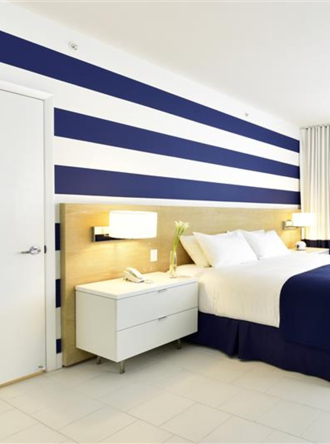 Moderne kamer met tweepersoonsbed, blauw-witte decoratie en daglicht.