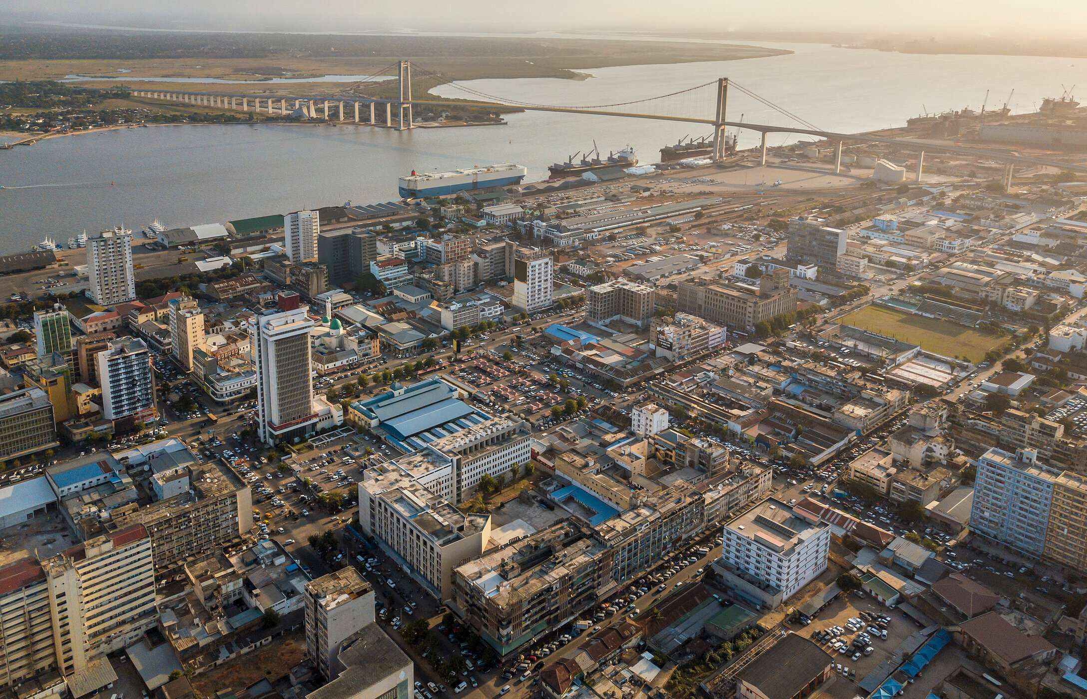 Vista aérea da cidade de Maputo, em Moçambique, com vários edifícios, carros, e uma ponte sobre um rio
