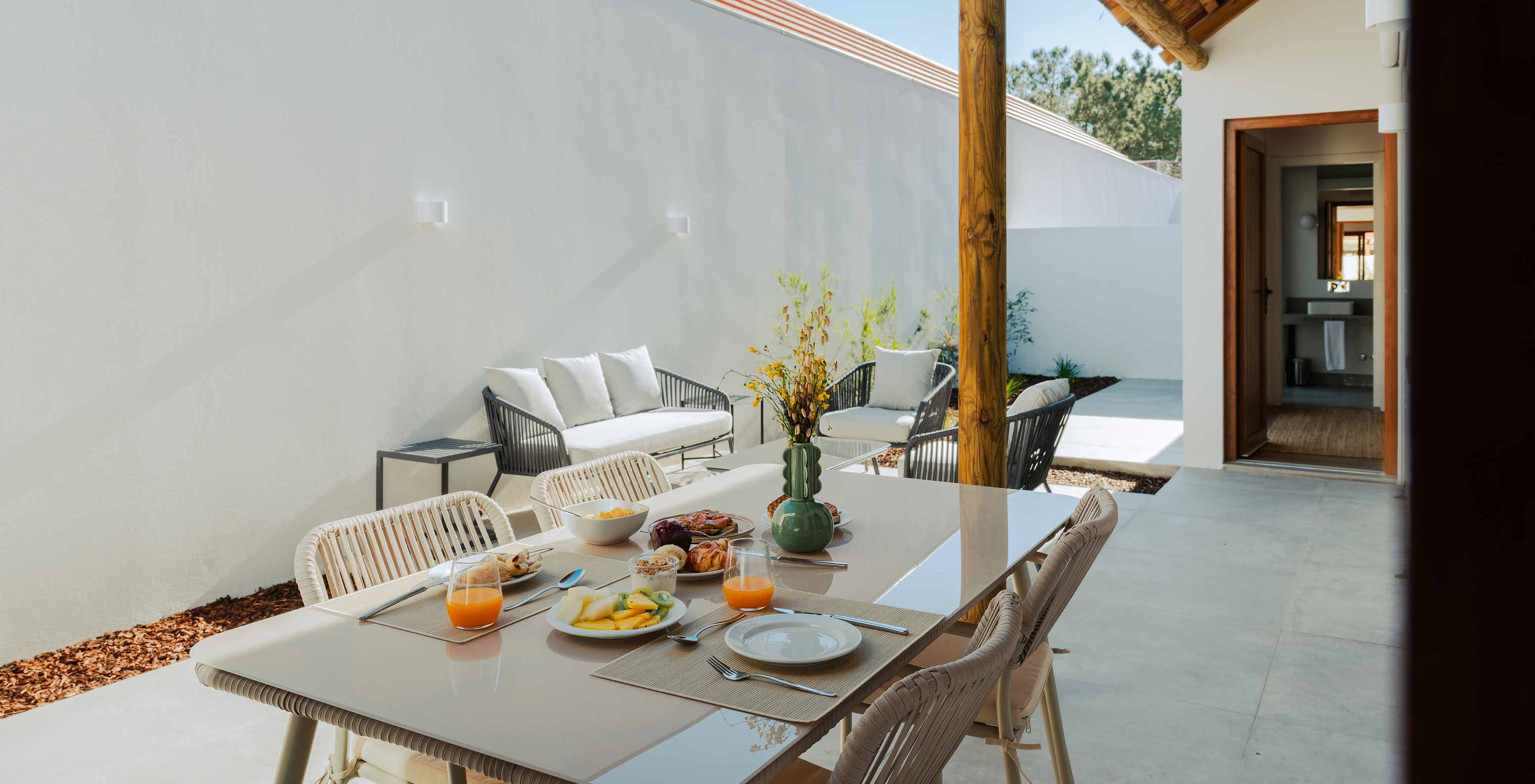 A Superior Villa do Pestana Comporta Village Residences tem um pátio exterior com uma mesa de refeição e um sofá